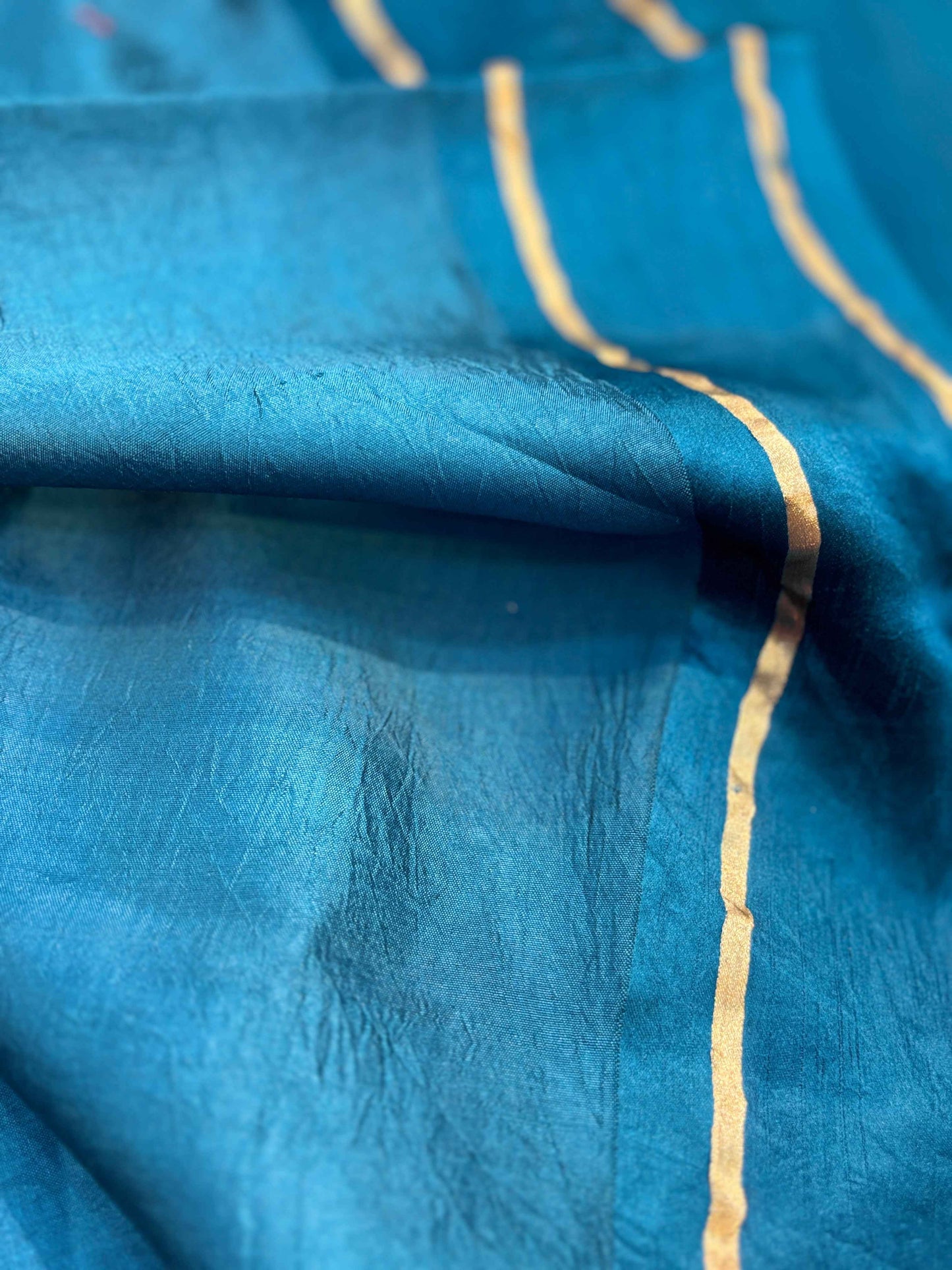 Dark blue saree fabric with gold zari piping along fold