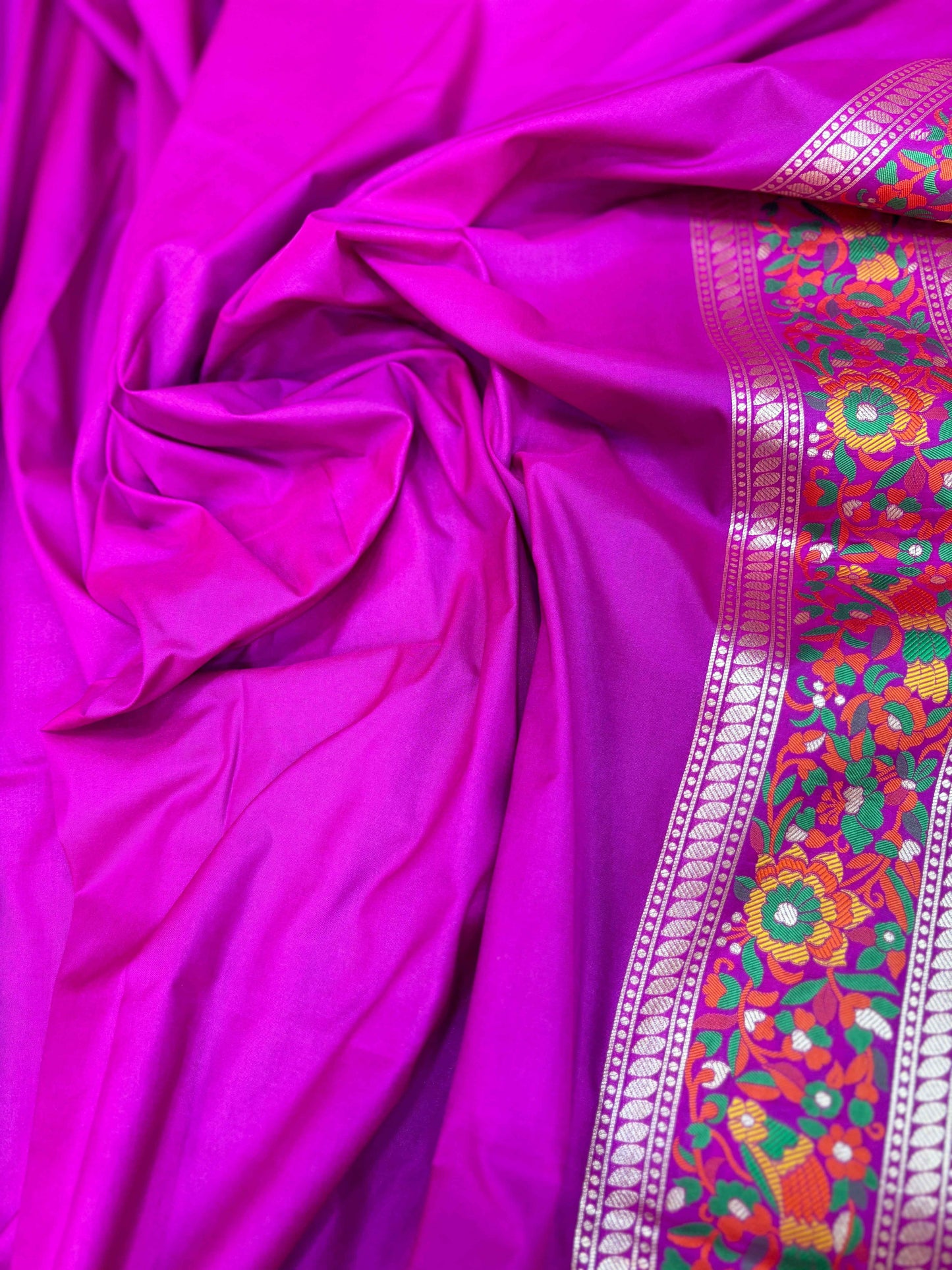 Pink saree fabric with multicolor floral embroidery along a contrast border stripe