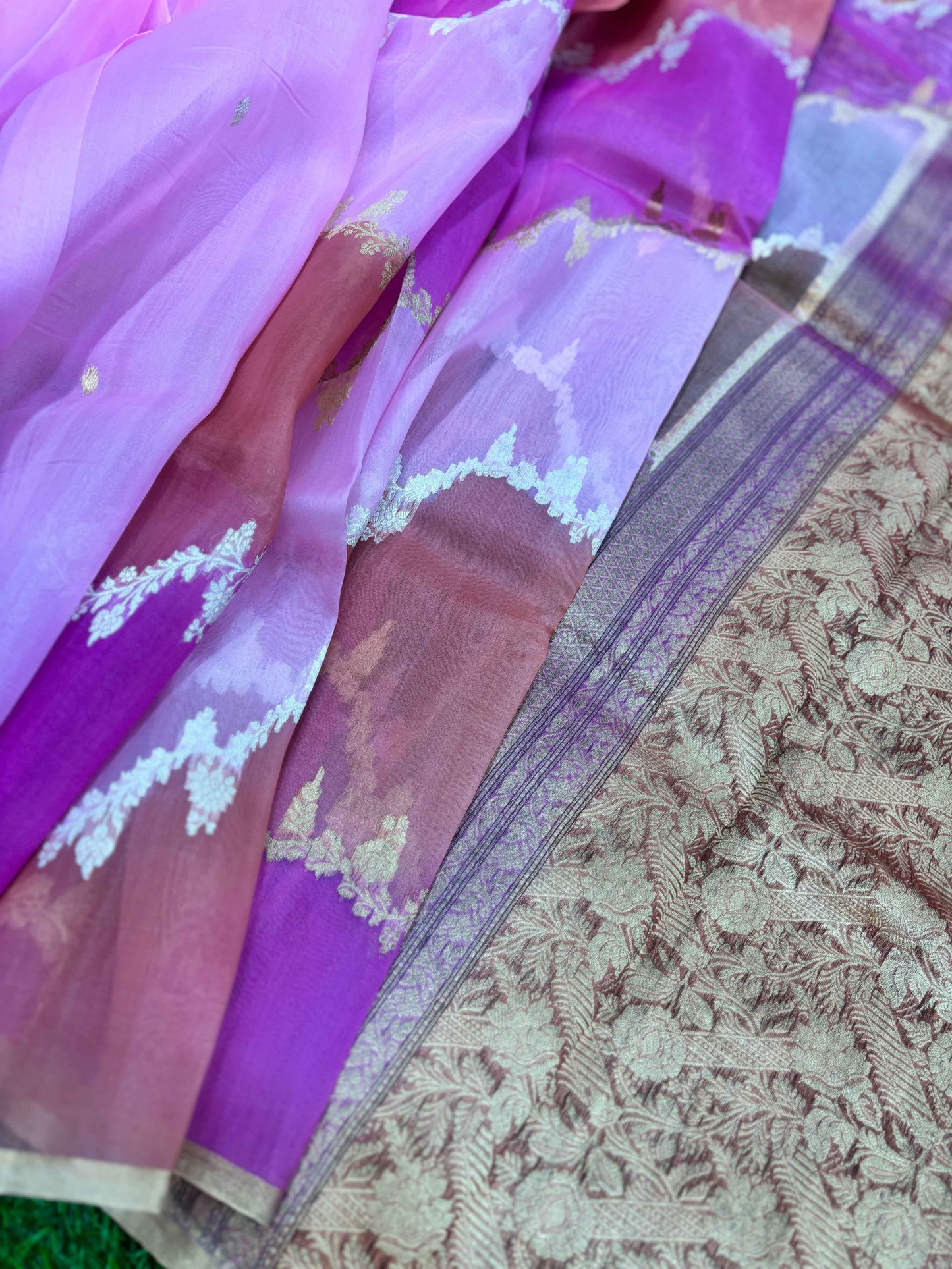 Lavender saree with woven motif band and ornate zari border over patterned fabric.