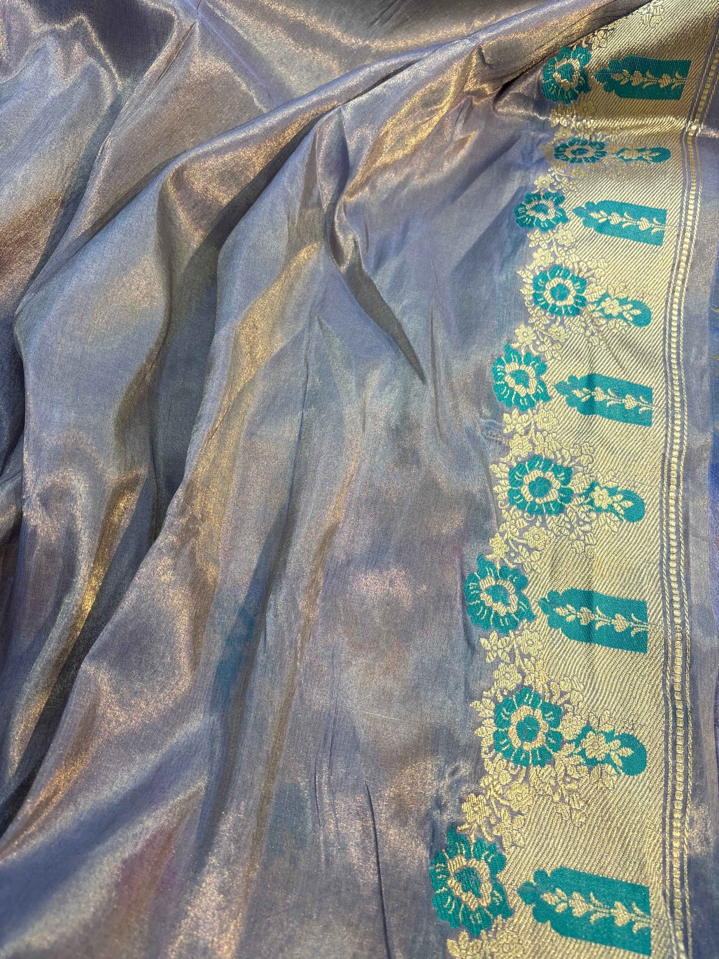 Metallic silver-blue saree edge with teal floral motifs and gold zari highlights