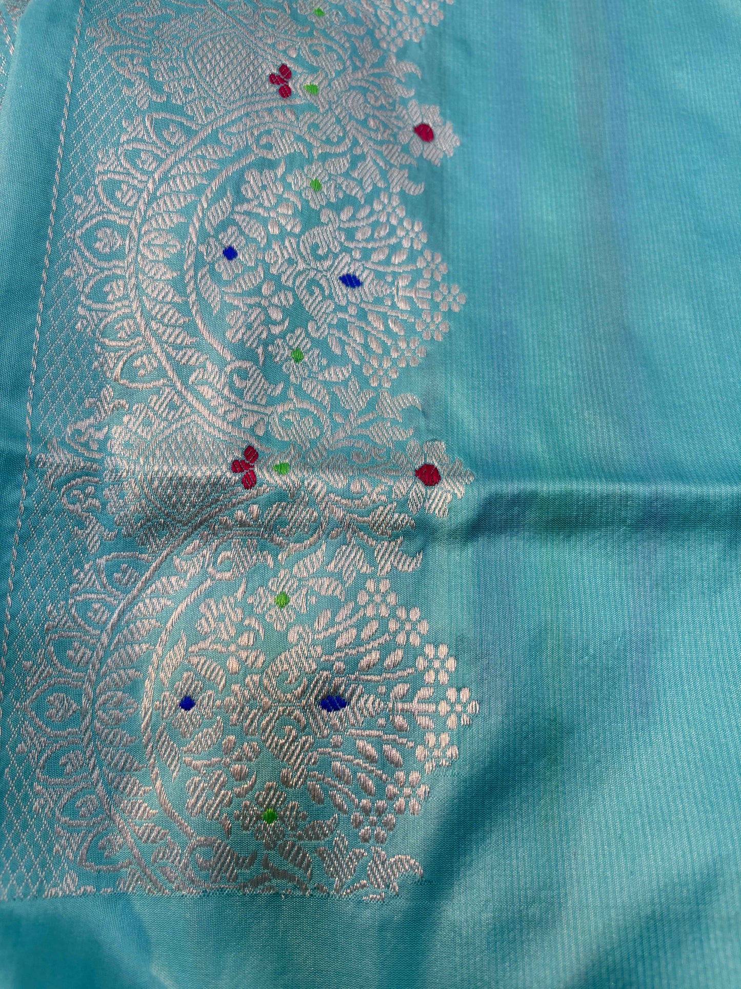 Powder blue saree with large embroidered floral medallion and scattered colorful accents
