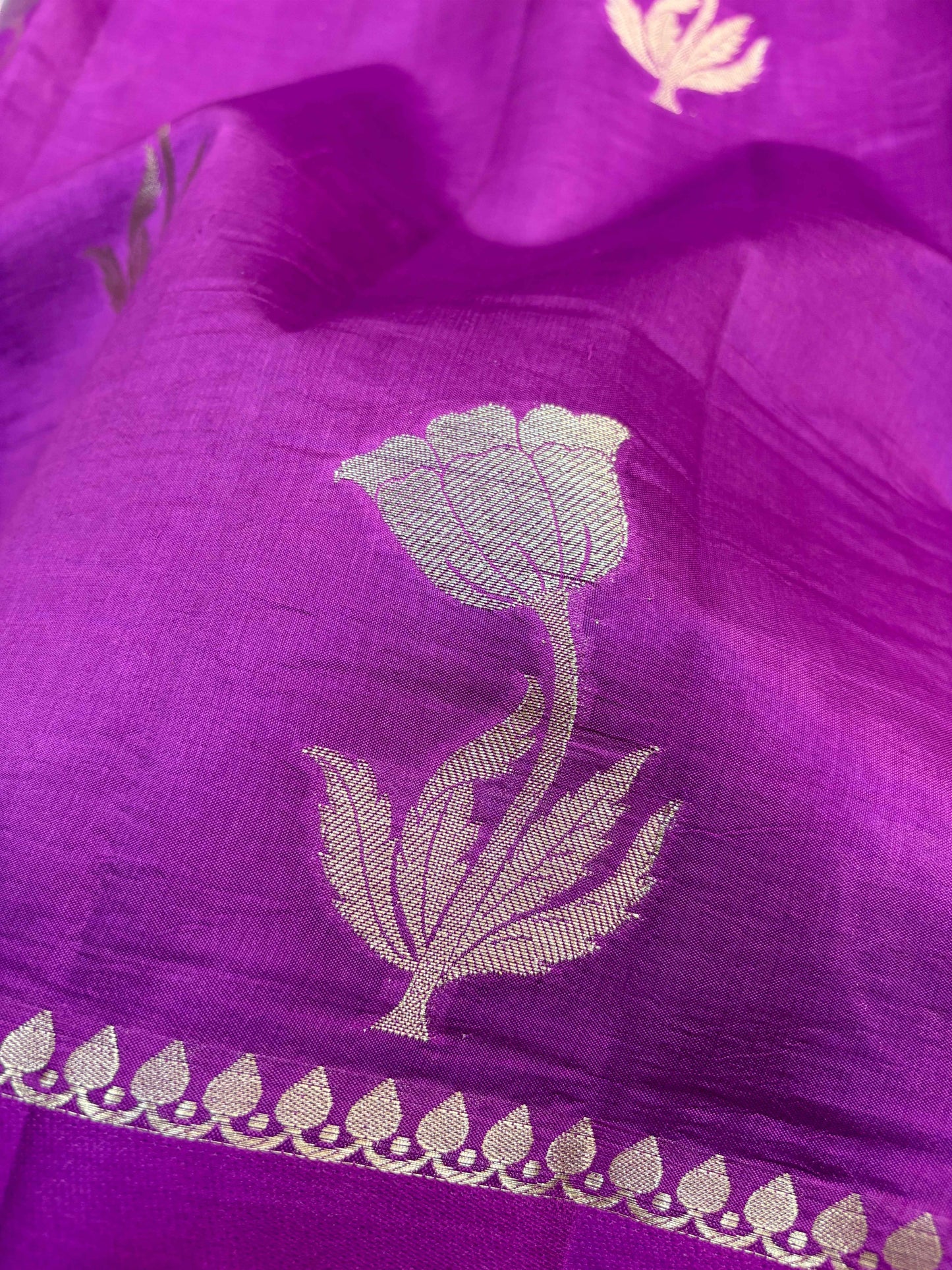 Rani pink saree close-up with large silver floral motif and zari trim