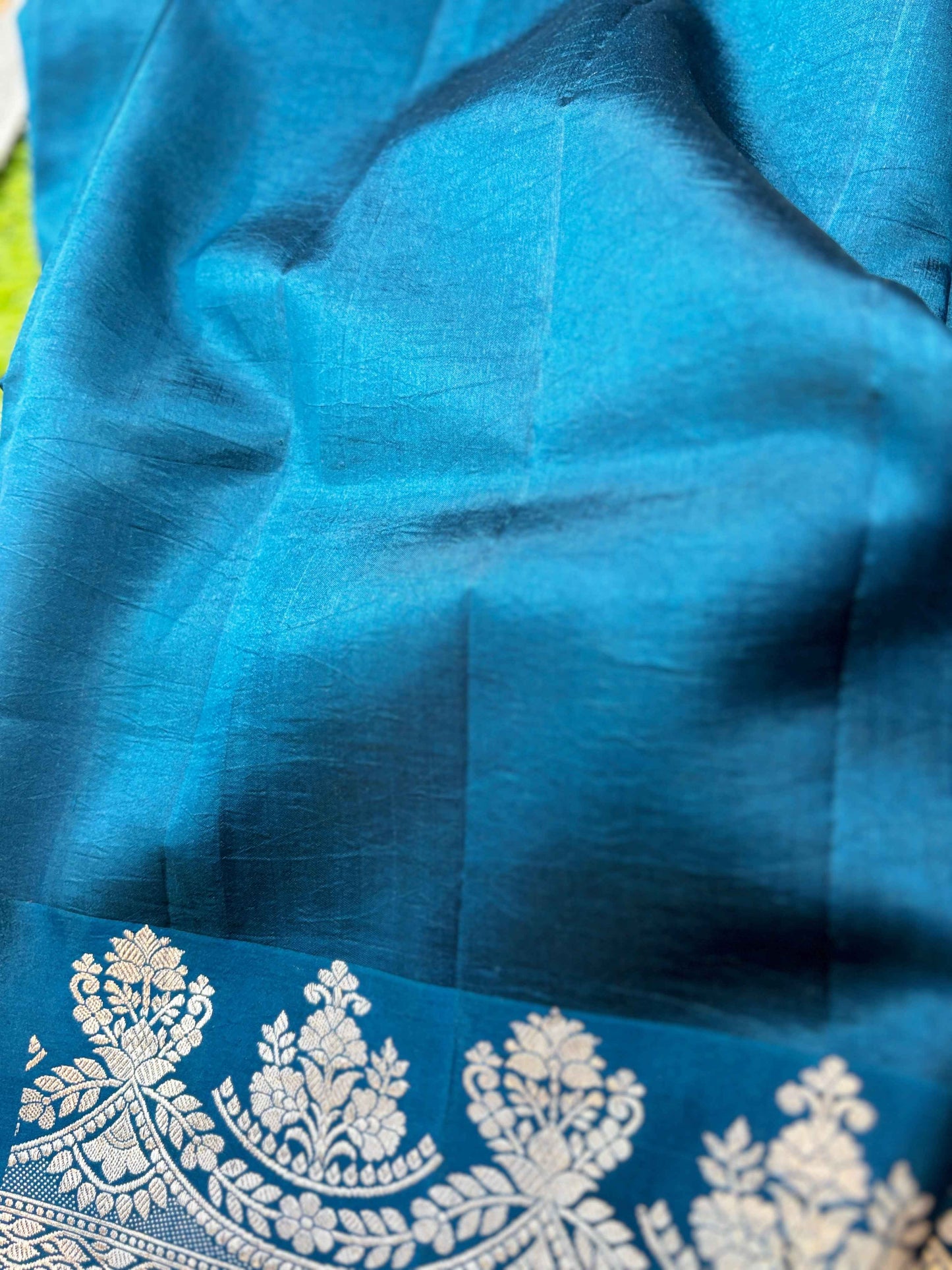 Sky blue saree fabric with ornate silver border detail and scattered leaf motifs