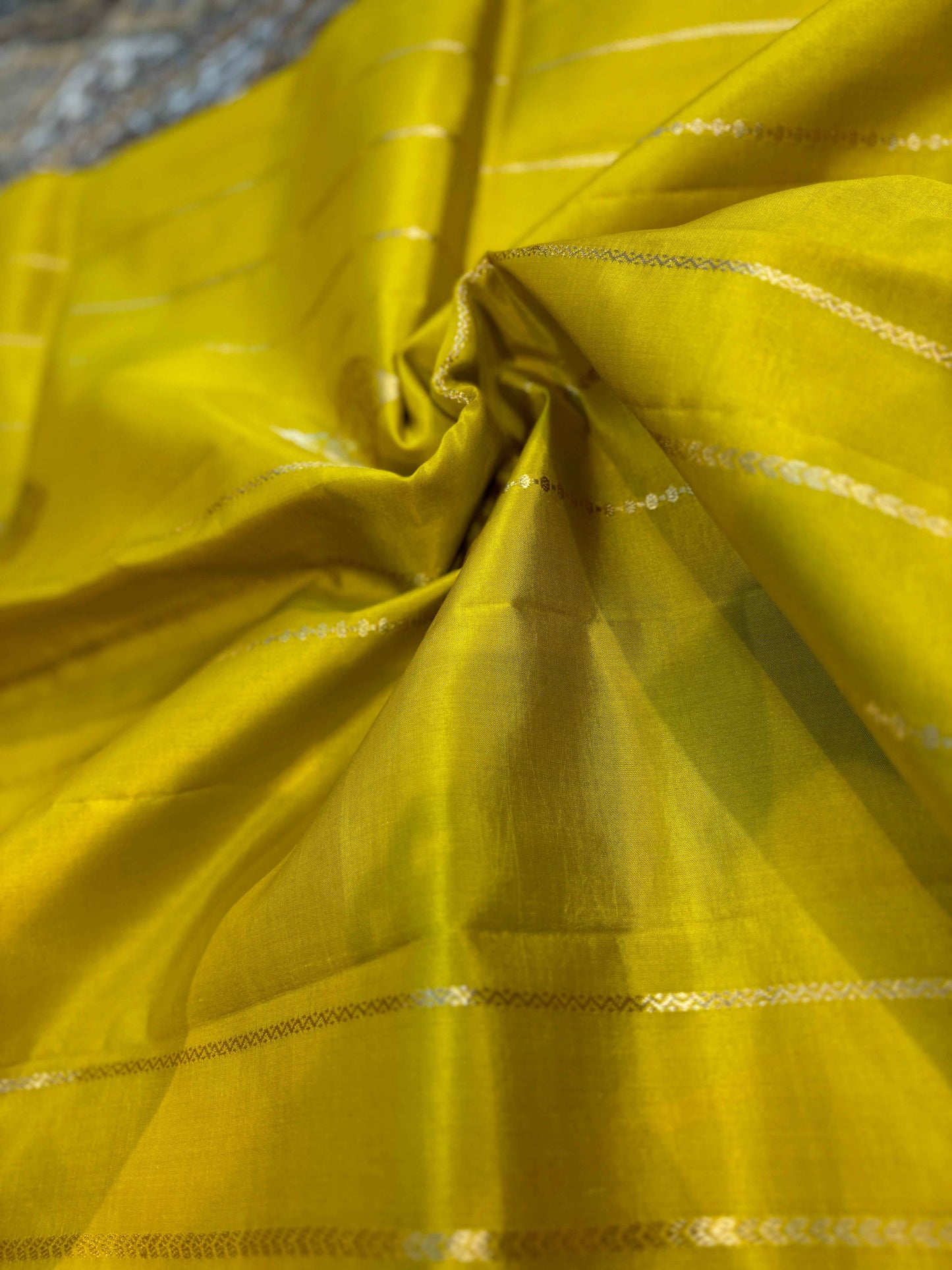 Mustard yellow saree with silver dotted lines across the pleats and zari border