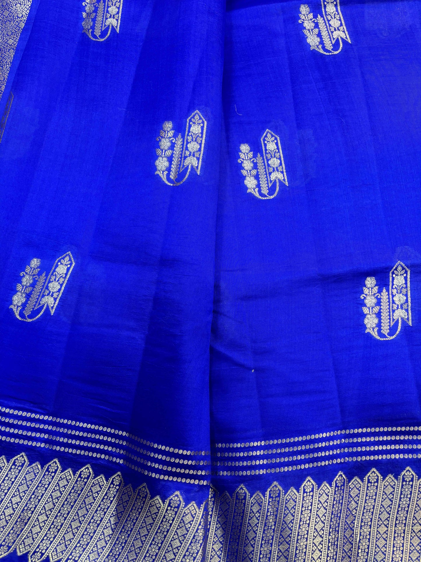 Blue saree with repeating vertical silver motifs and zari border along edge