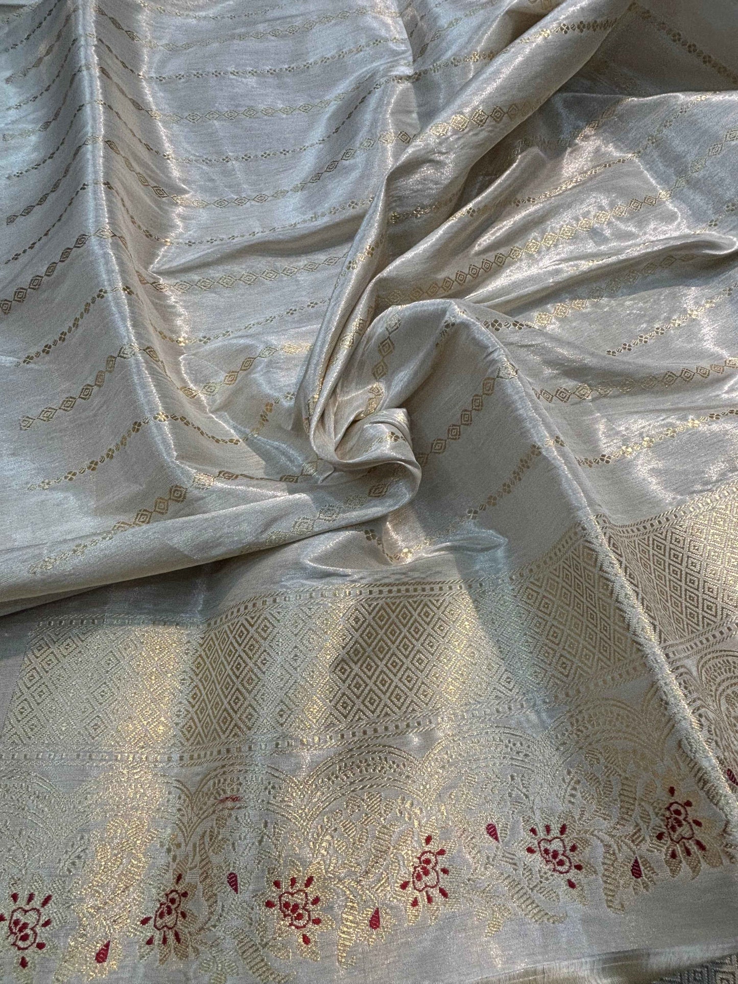 White saree fabric close-up with multicolor buta and textured zari border