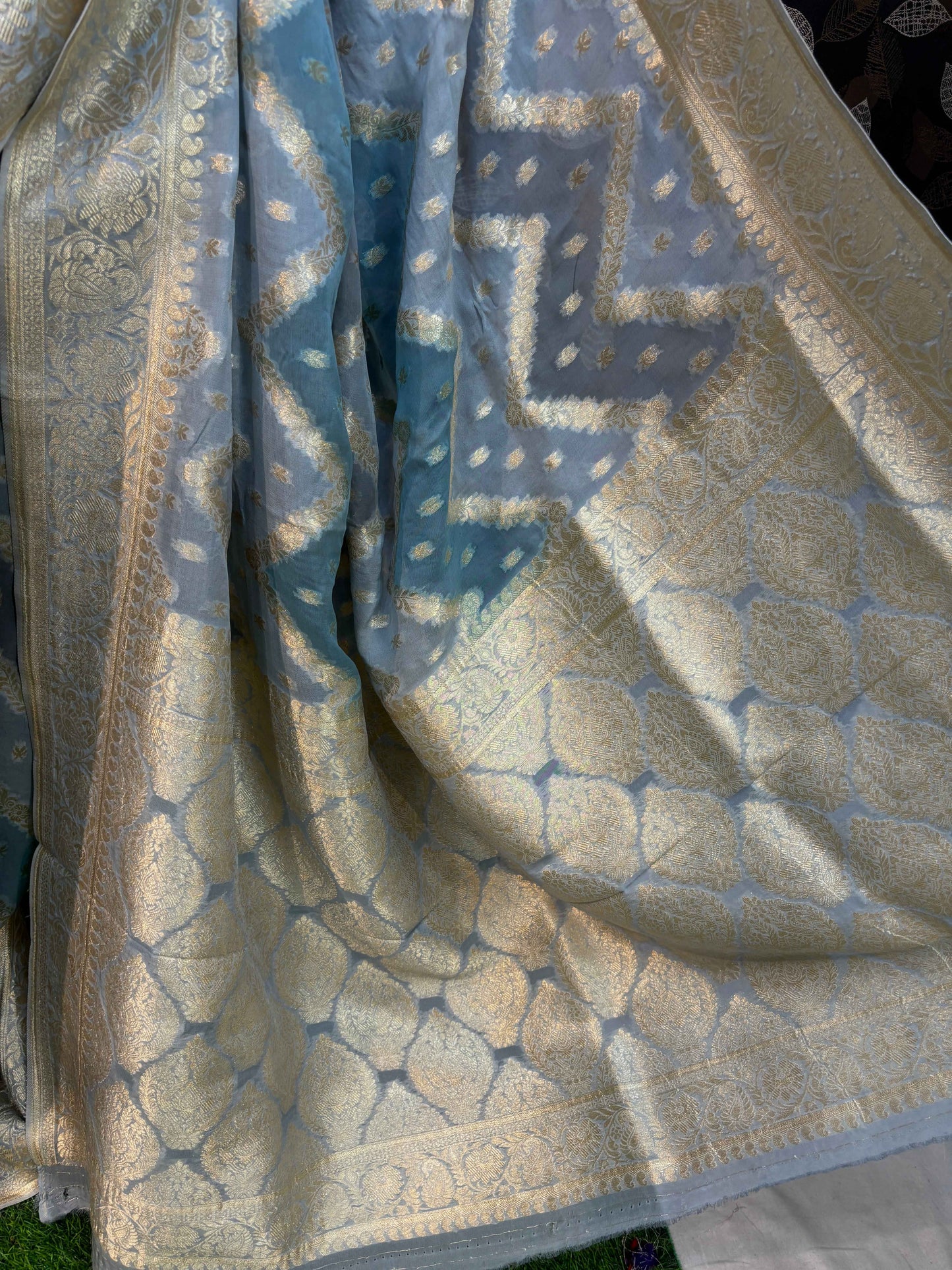 Light blue georgette saree with gold-toned ornate leaf and scale motifs; wide gold border