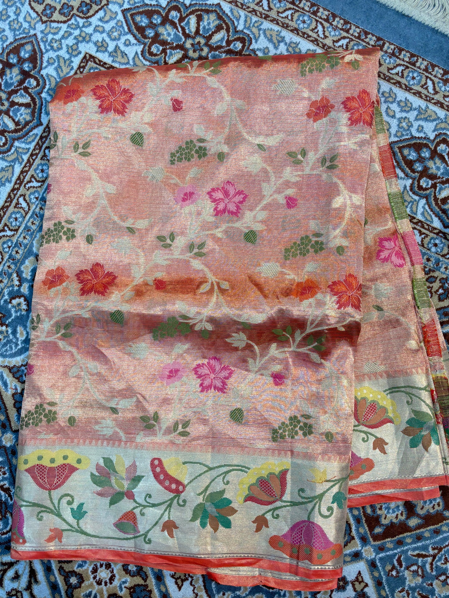 Pink sheer saree folded with scattered floral motifs, multicolor bird-and-vine border