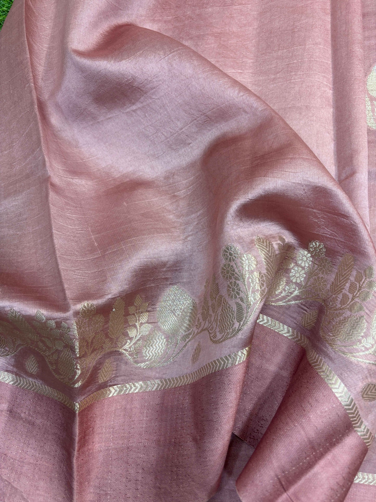 Mauve-pink saree fabric close-up with woven vine motif band in silver-gold.