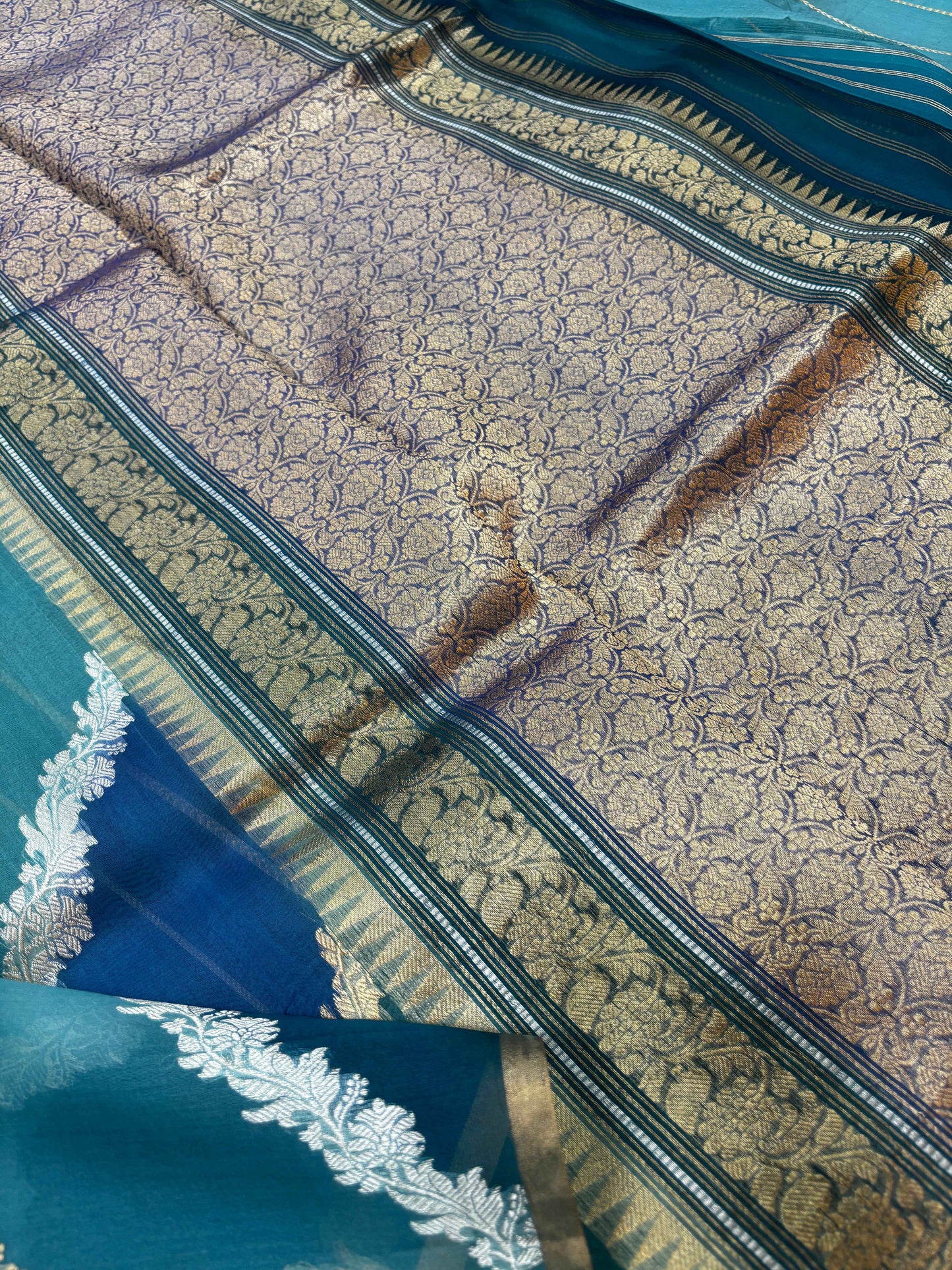 Saree border close-up with ornate patterned panel and blue-green stripe detailing