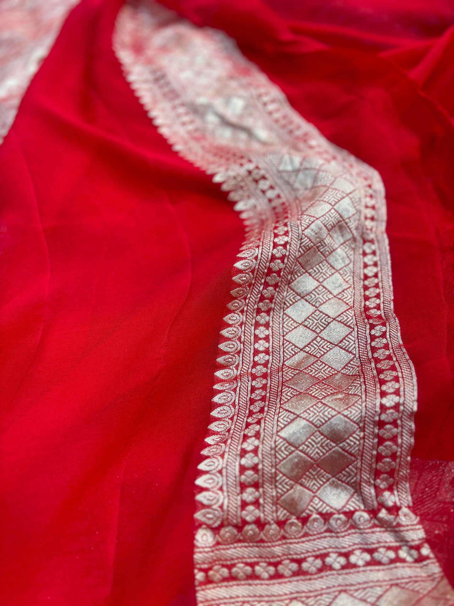 Red saree border with intricate white embroidery and diamond pattern trim