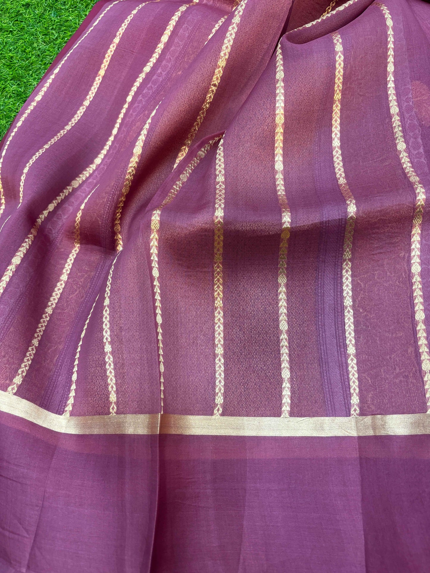 Dark purple-pink saree drape with gold vertical chain stripes and wide zari border.