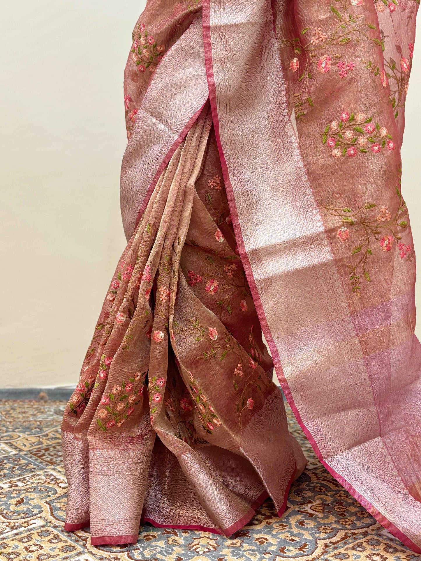 Light pink crepe tissue sari fabric close-up with gold embroidery and striped border