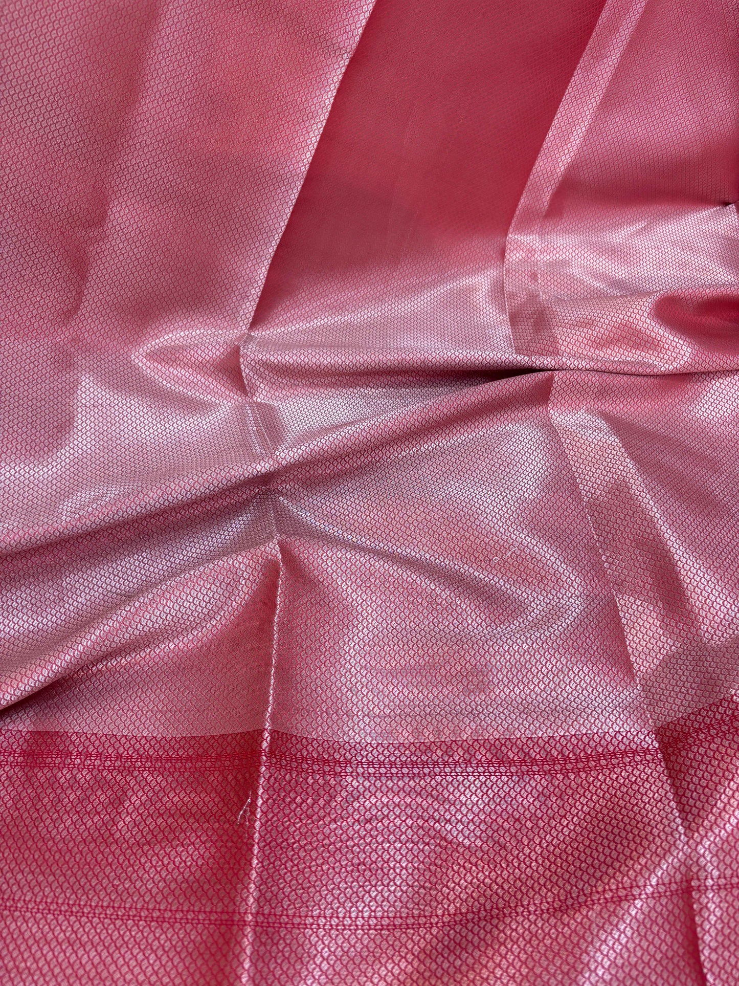 Pink-red saree fabric with subtle woven texture and small patterned dots