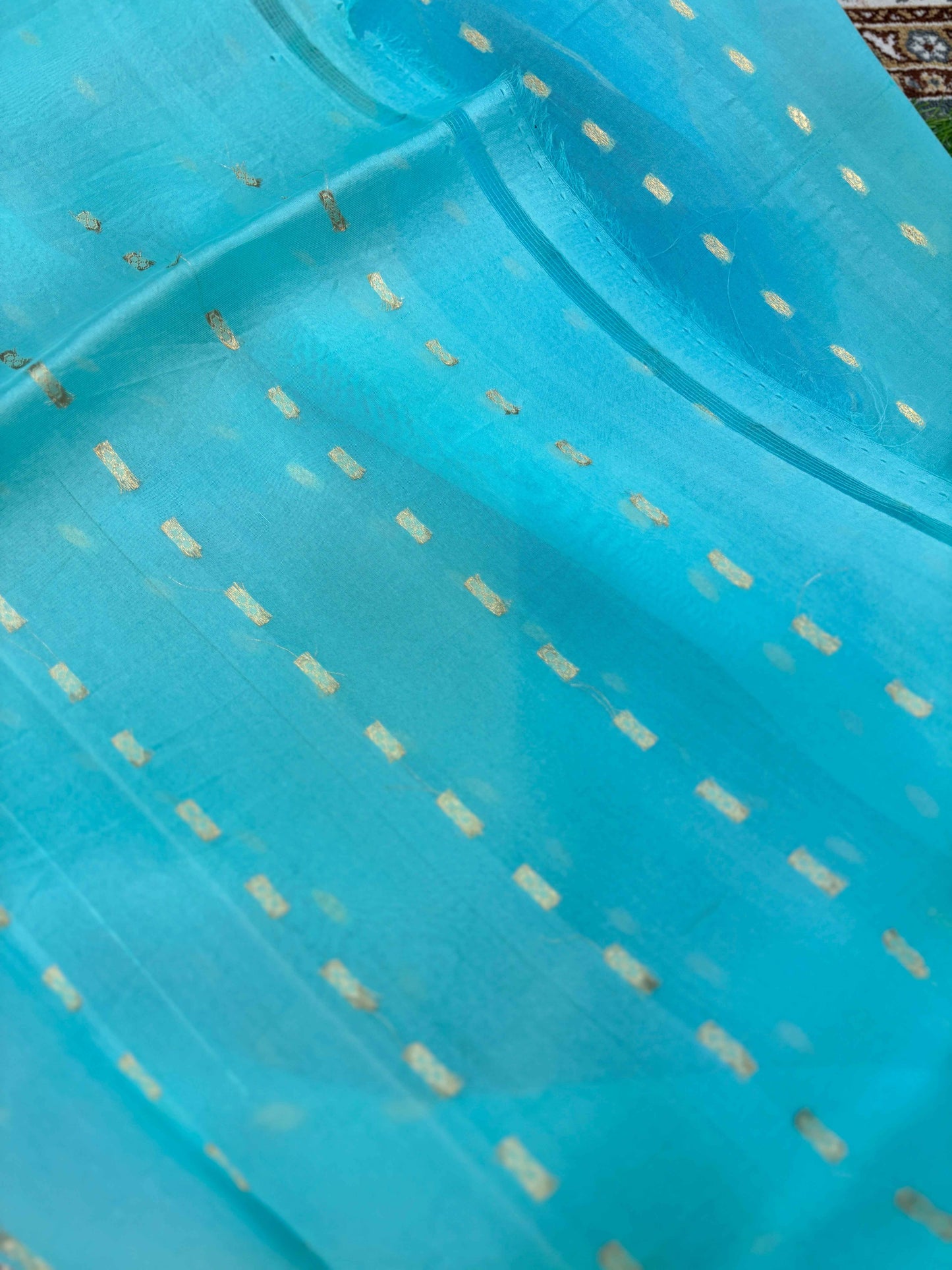 Sky blue saree fabric close-up with small gold zari dash motifs