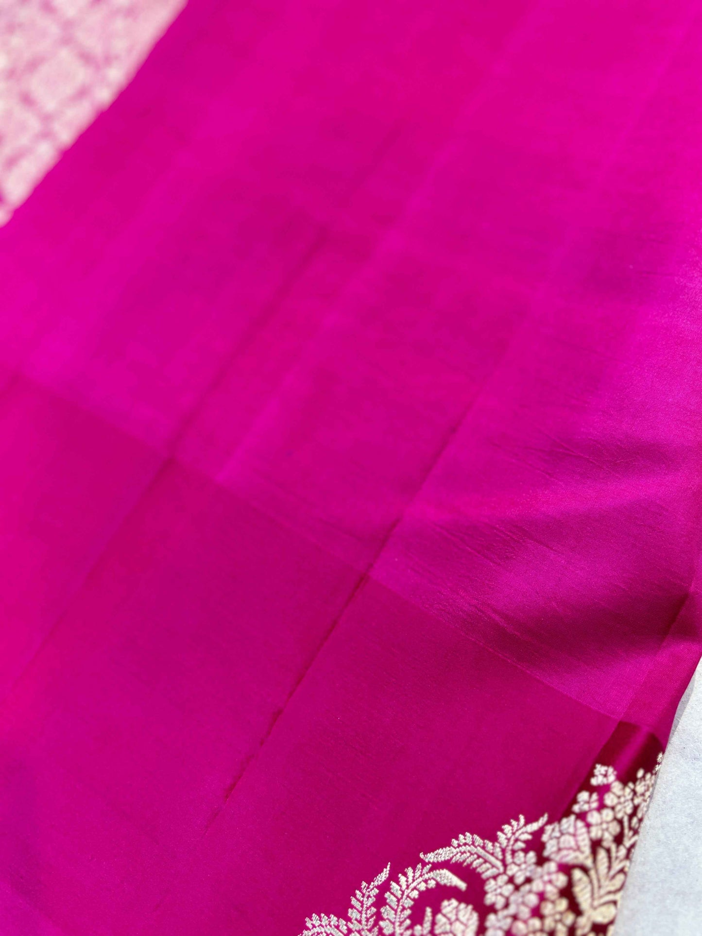 Rani pink saree fabric with fine sheen and partial floral zari motif