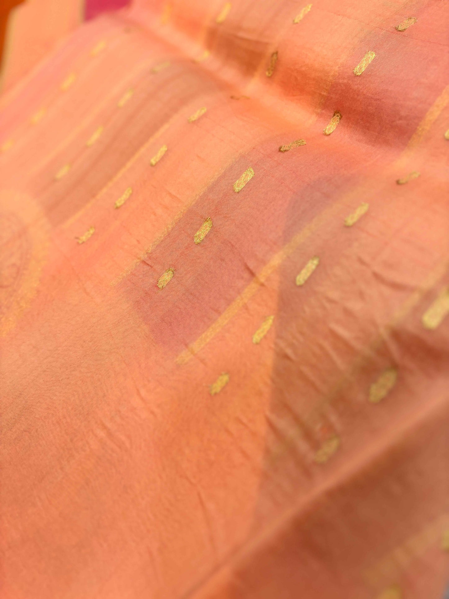Light orange Banarasi saree close-up with scattered gold thread dots