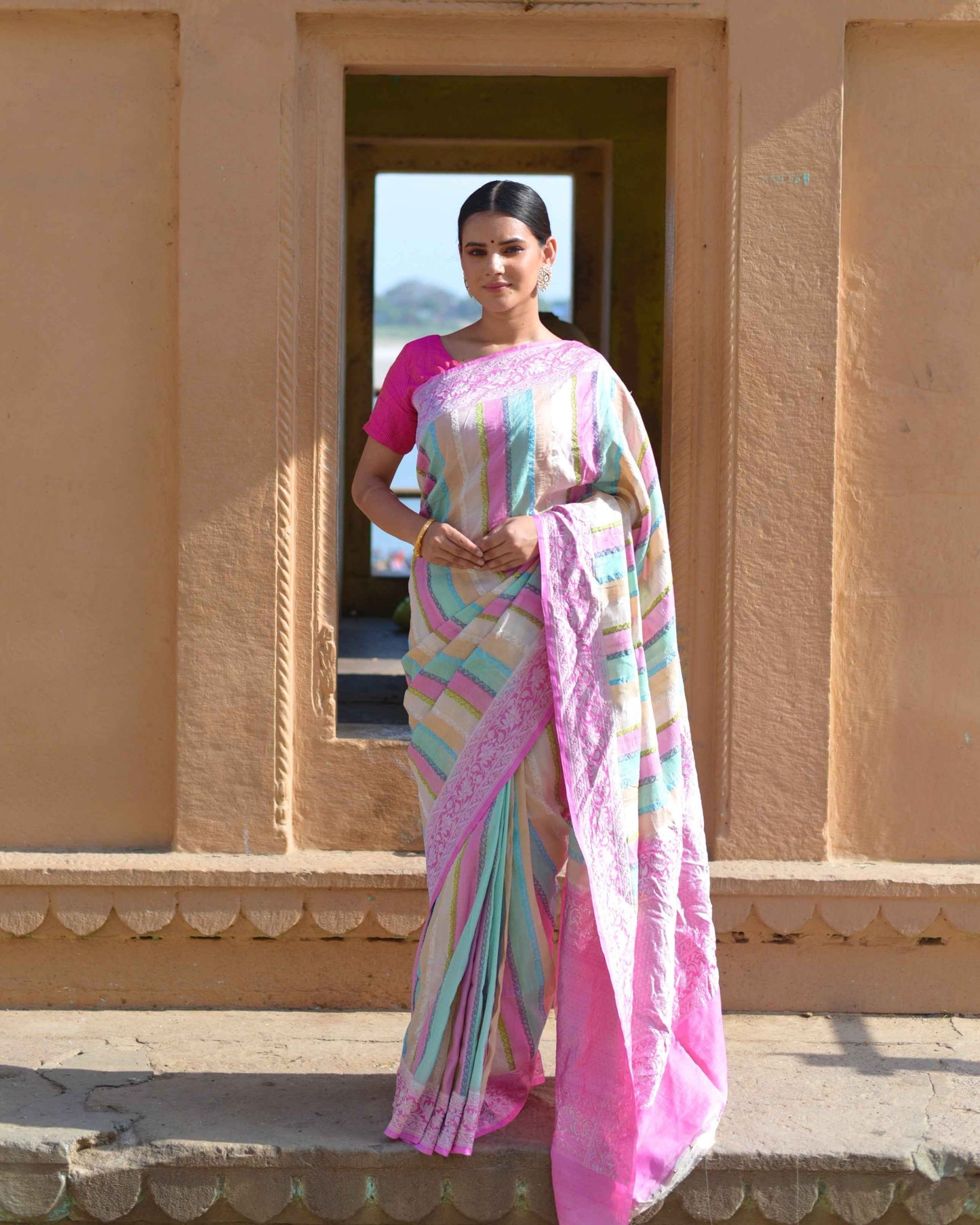 Pink tussar georgette saree with multicolor striped border, draped on model