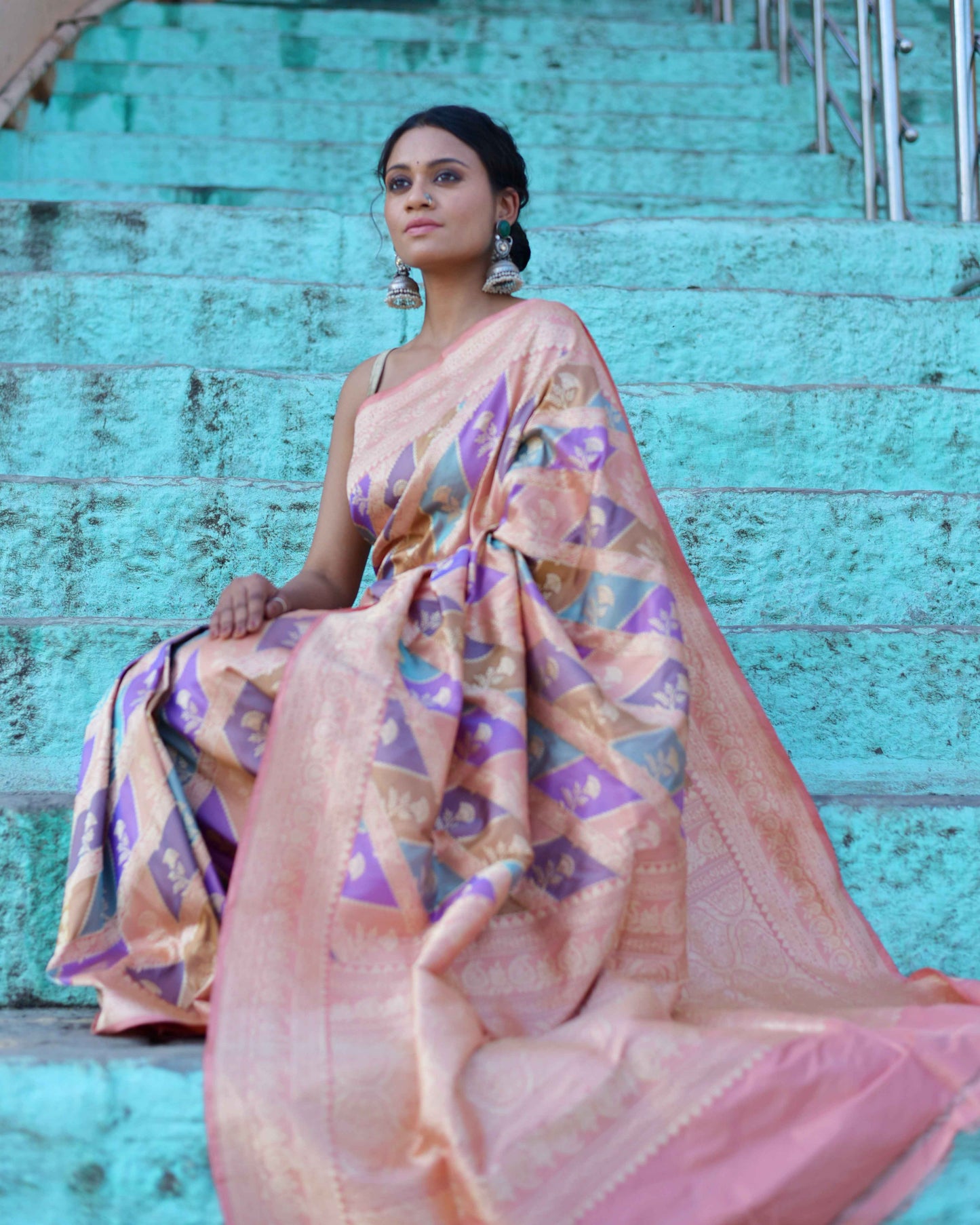 Peach saree draped with purple-gold motif panels and textured peach border.