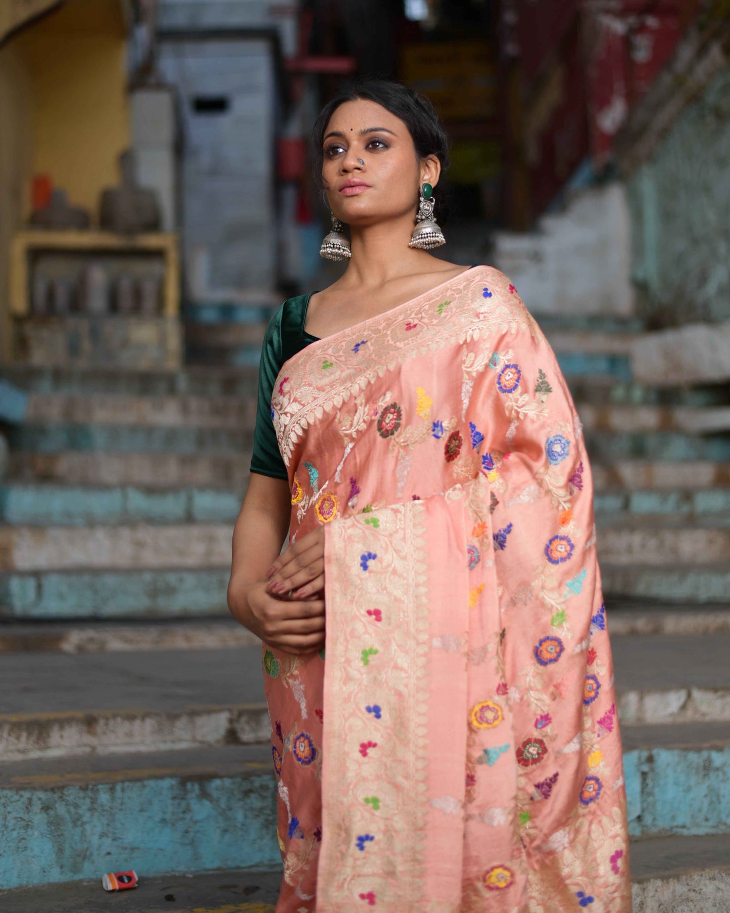 Peach pink handloom saree with multicolor floral motifs and ornate cream border, draped