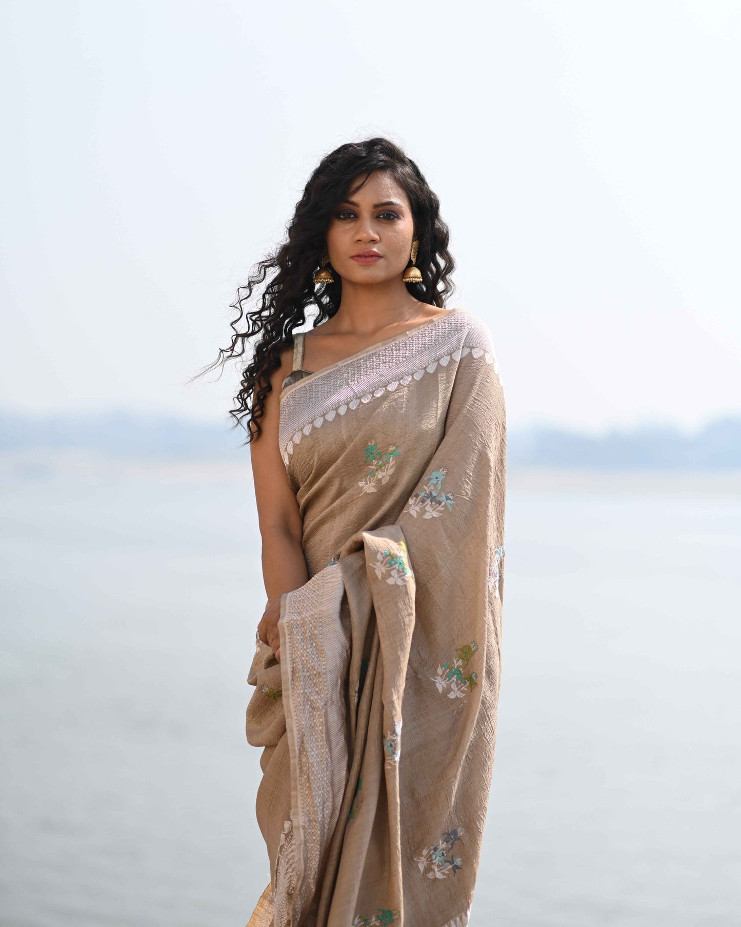 Beige tussar georgette saree with light border and green floral motifs on pallu