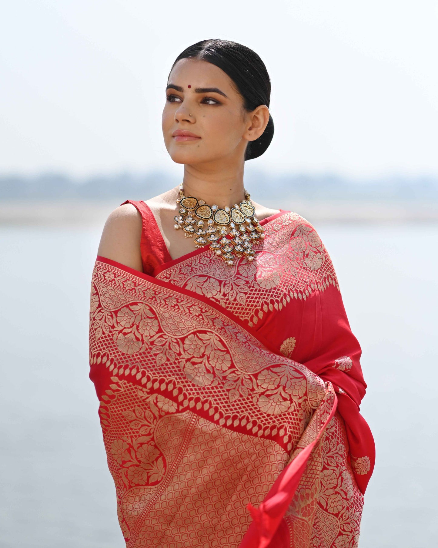 Red sari with detailed golden buti pattern and wide woven border, pleated drape