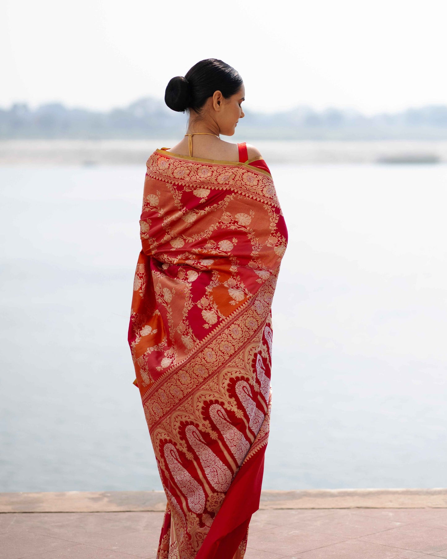 Red silk saree with gold border and ornate paisley motifs, pallu draped over shoulder
