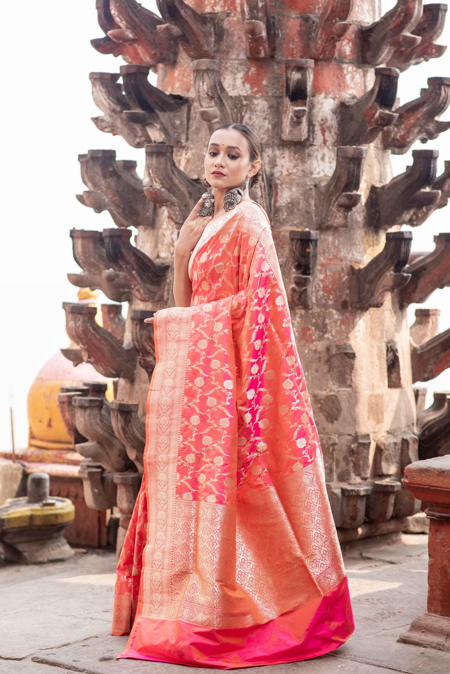 Coral pink saree with gold border, patterned body, and draped pallu
