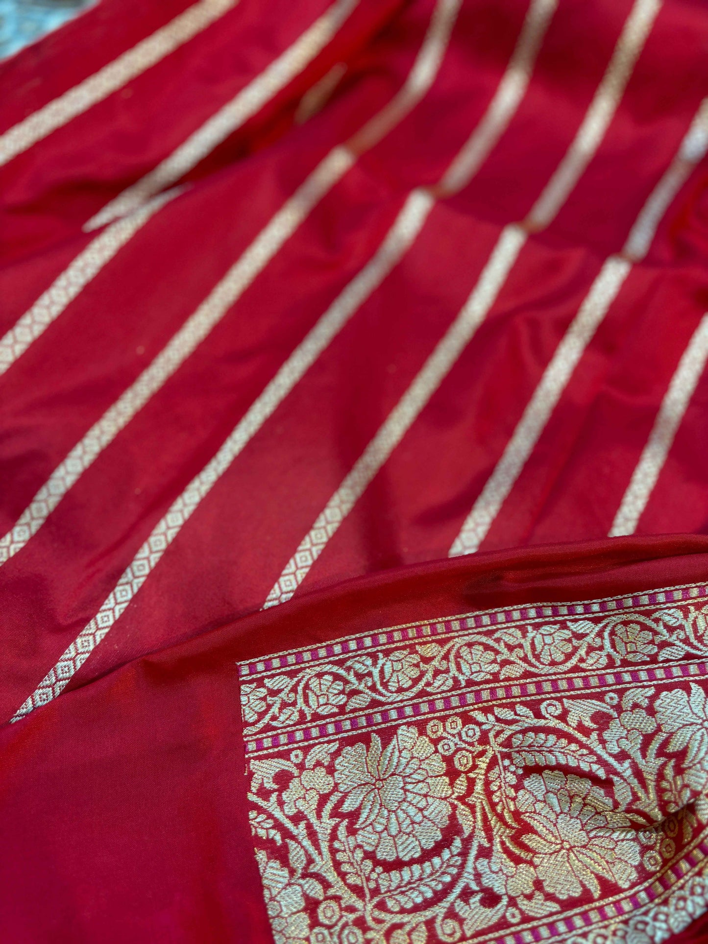 Red saree with gold striped sheen and ornate paisley zari border