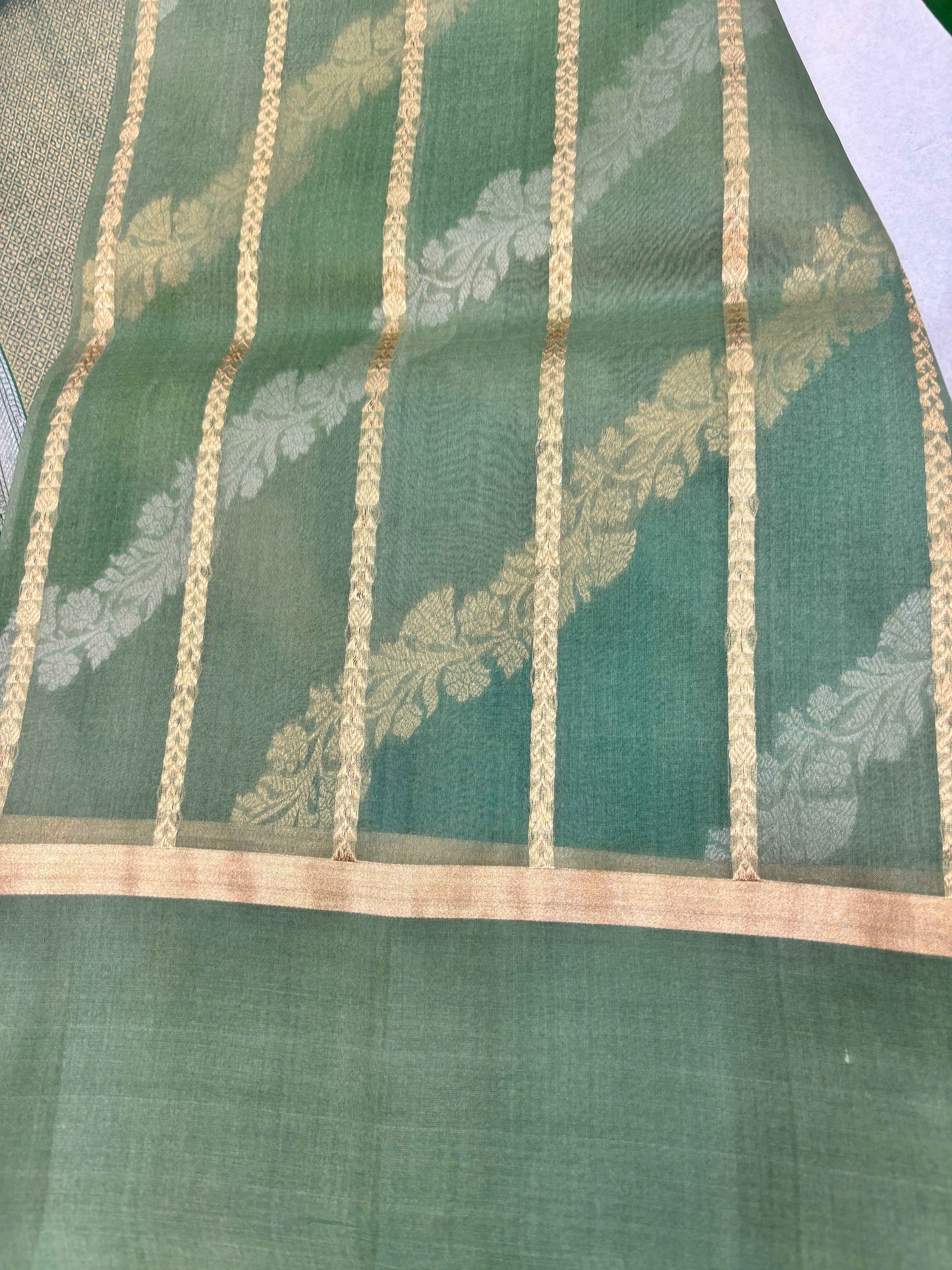 Light green saree with vertical gold-and-cream stripes and woven floral motifs