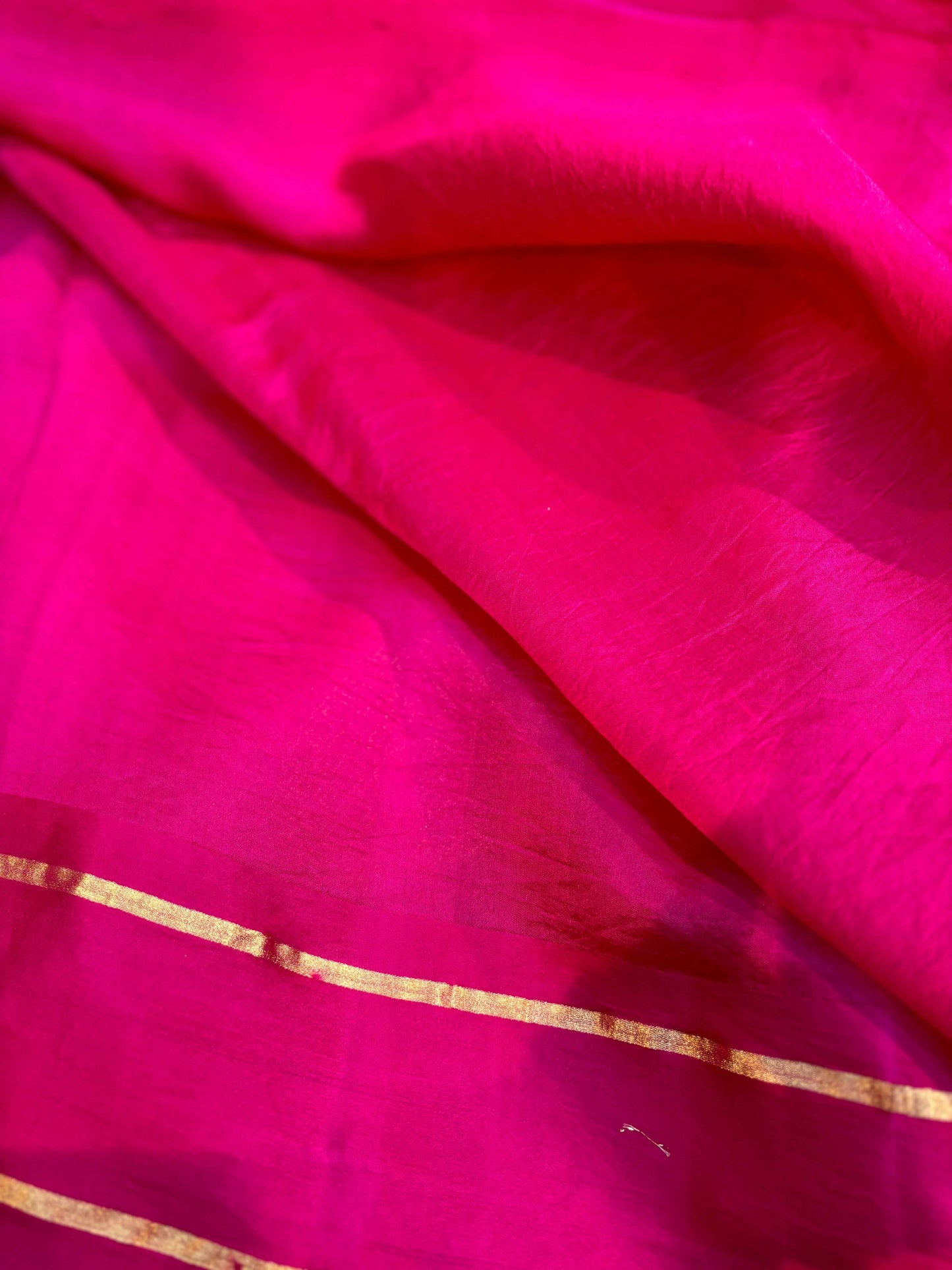 Pink saree with gold zari strip along hem on smooth fabric