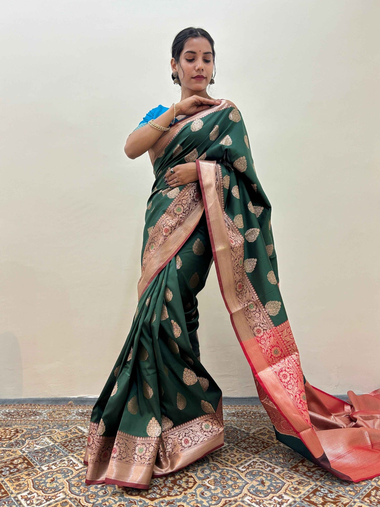 Green silk saree draped on model with gold motifs and rose-pink patterned border