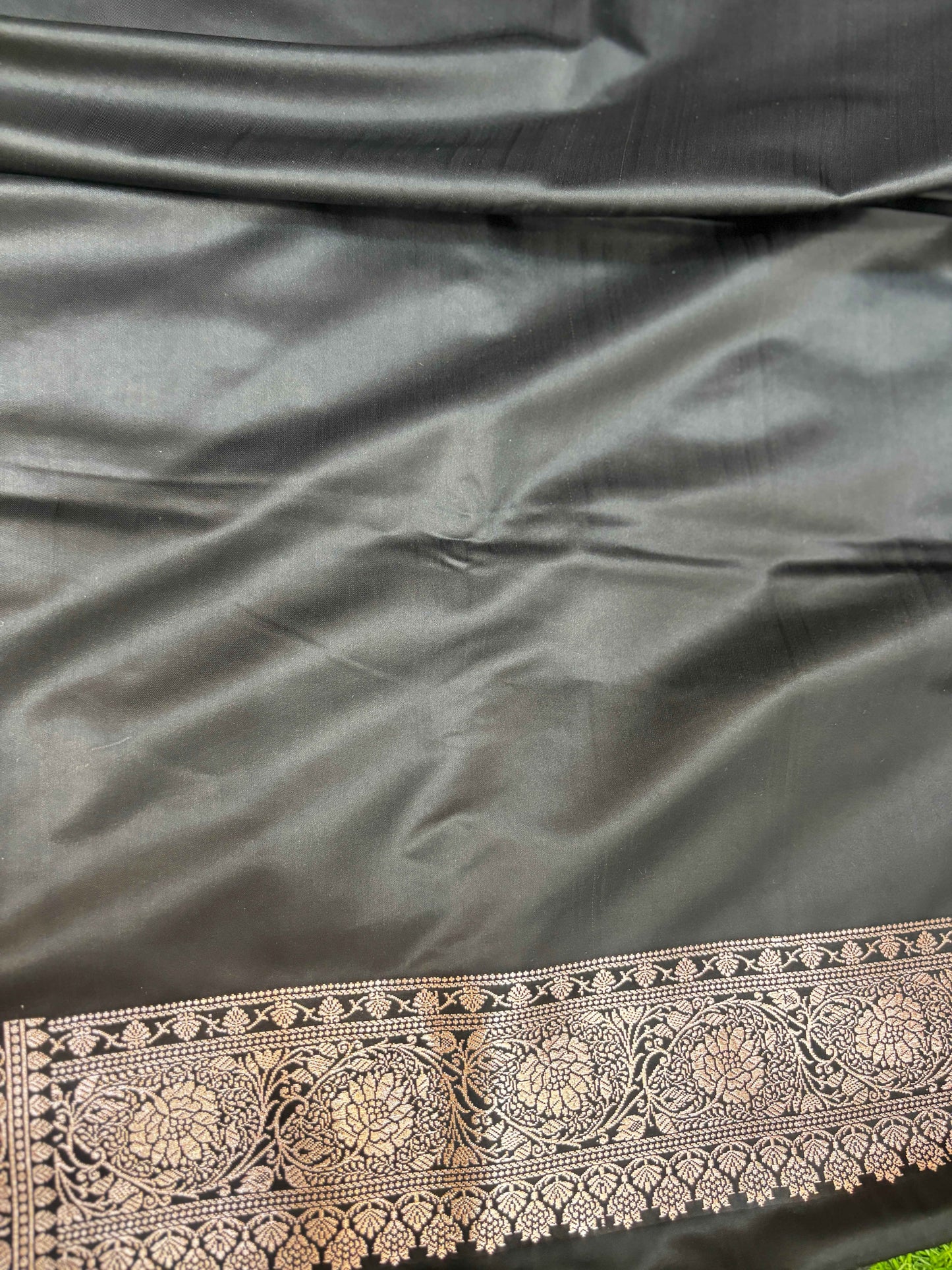 Black saree fabric with silver-gold ornate zari border at lower edge
