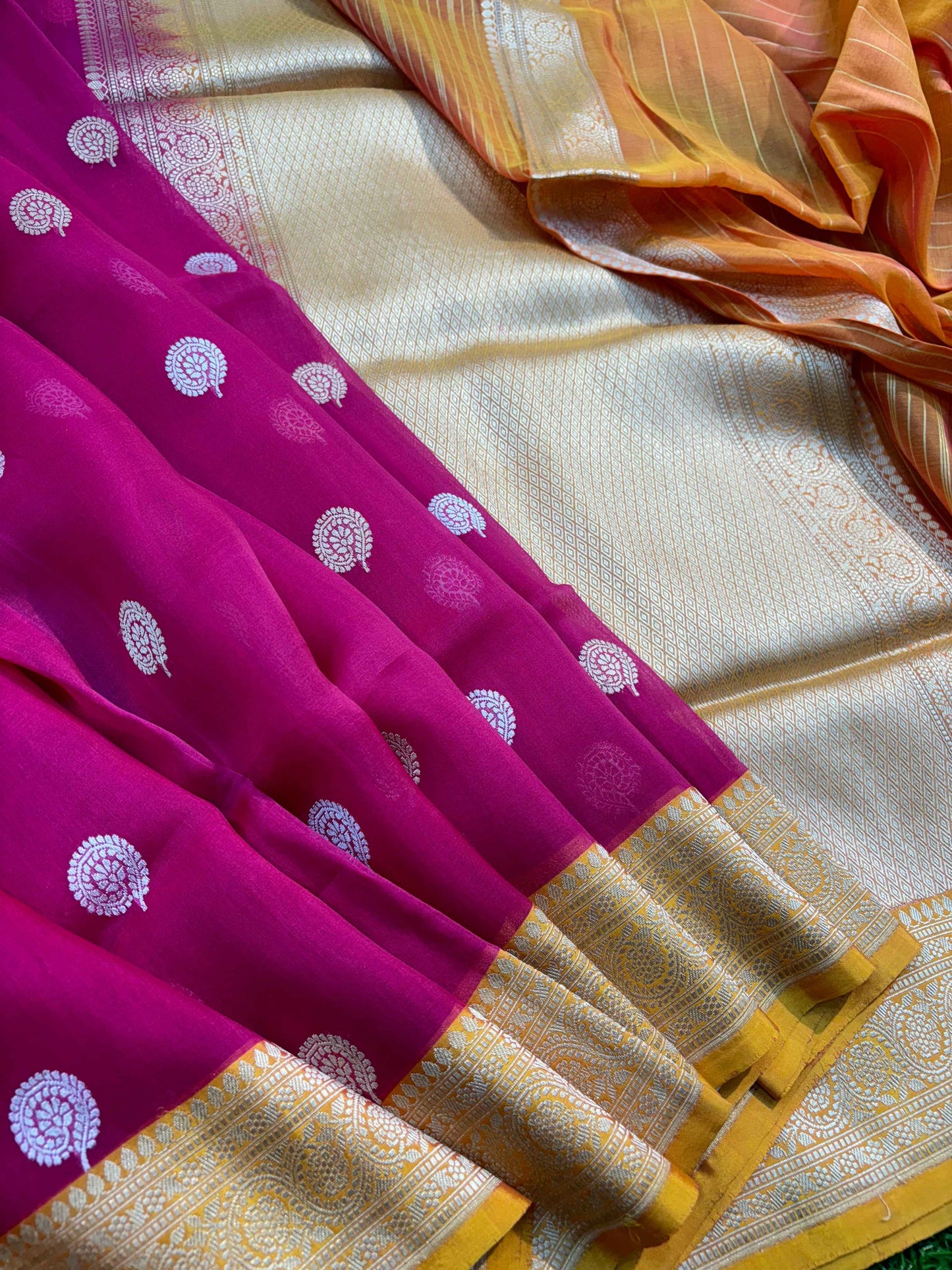 Rani pink saree with circular motifs and gold zari border on off-white base