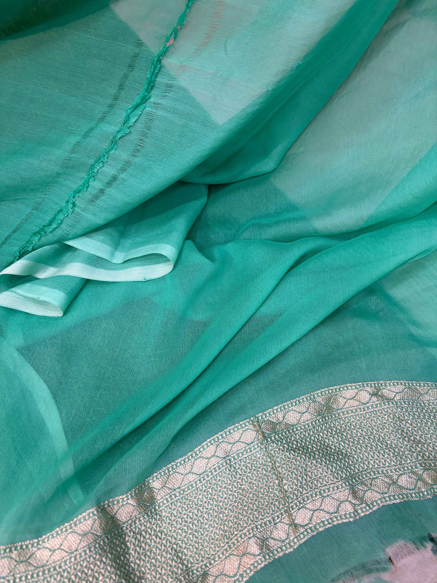 Teal-green saree fabric with delicate patterned border and textured weave