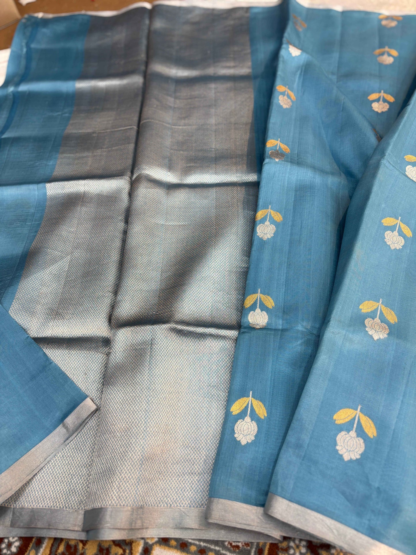 Powder-blue saree draped with silver body and patterned gold motifs along border