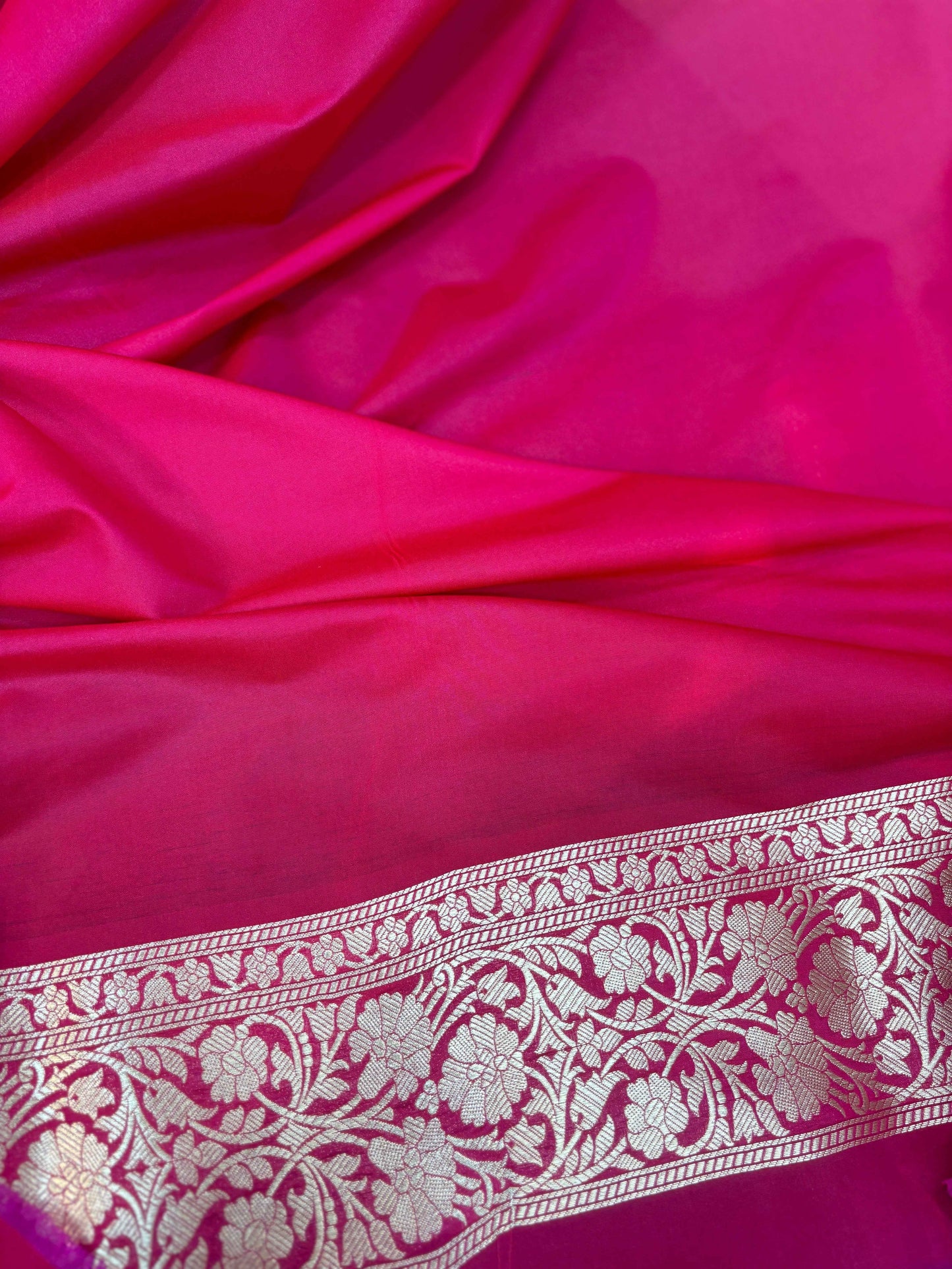 Red Banarasi silk close-up with woven floral border band along edge