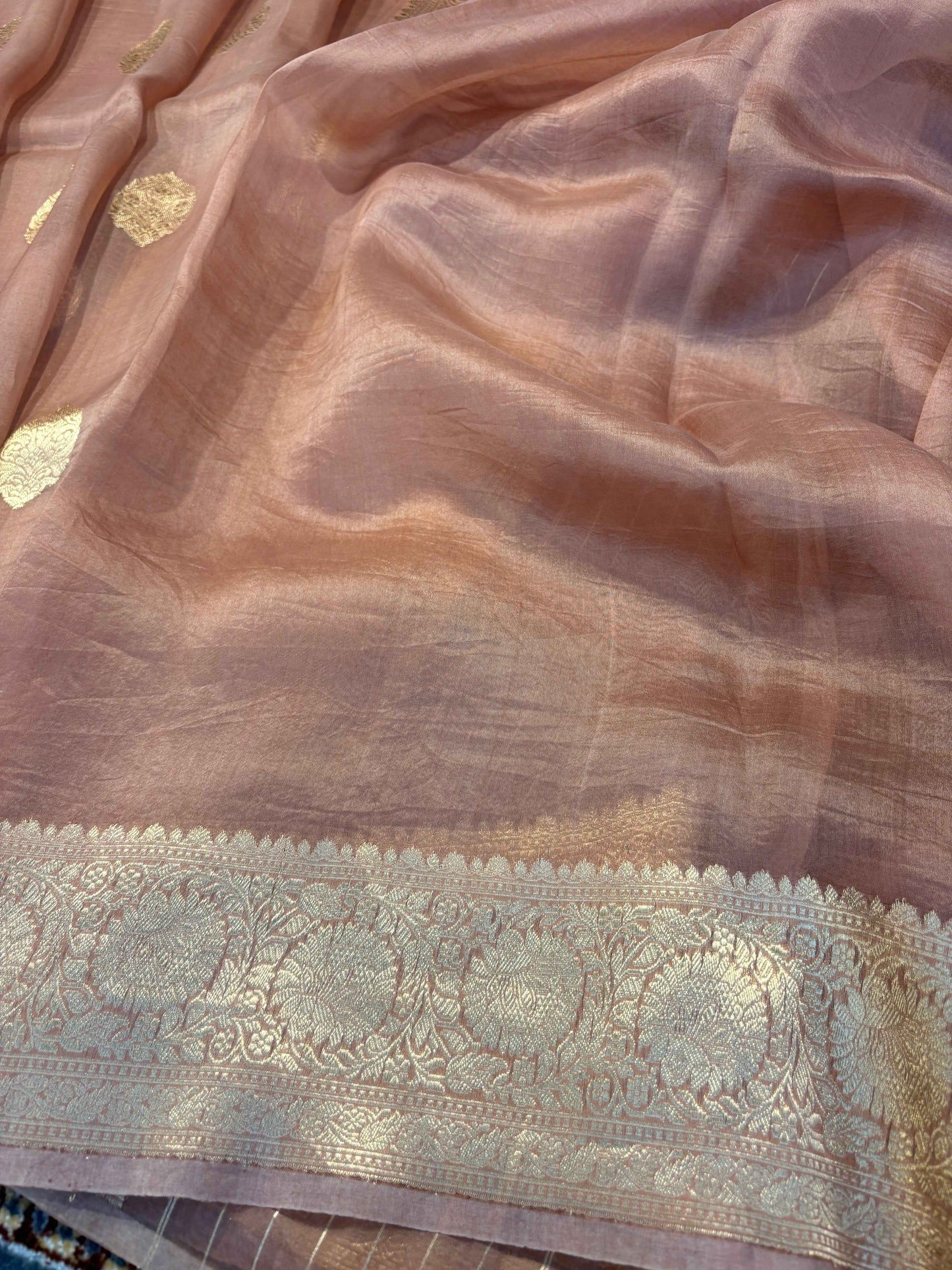 Light brown saree fabric with scattered gold leaf motifs and ornate woven border