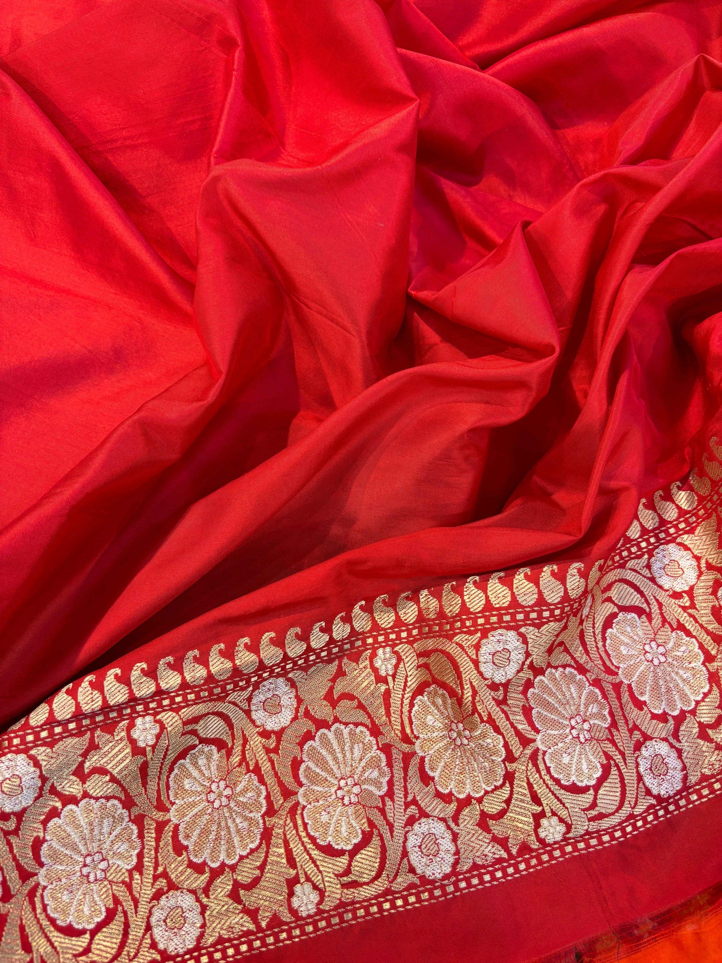 Red Banarasi saree with patterned red border and beige underside with floral work