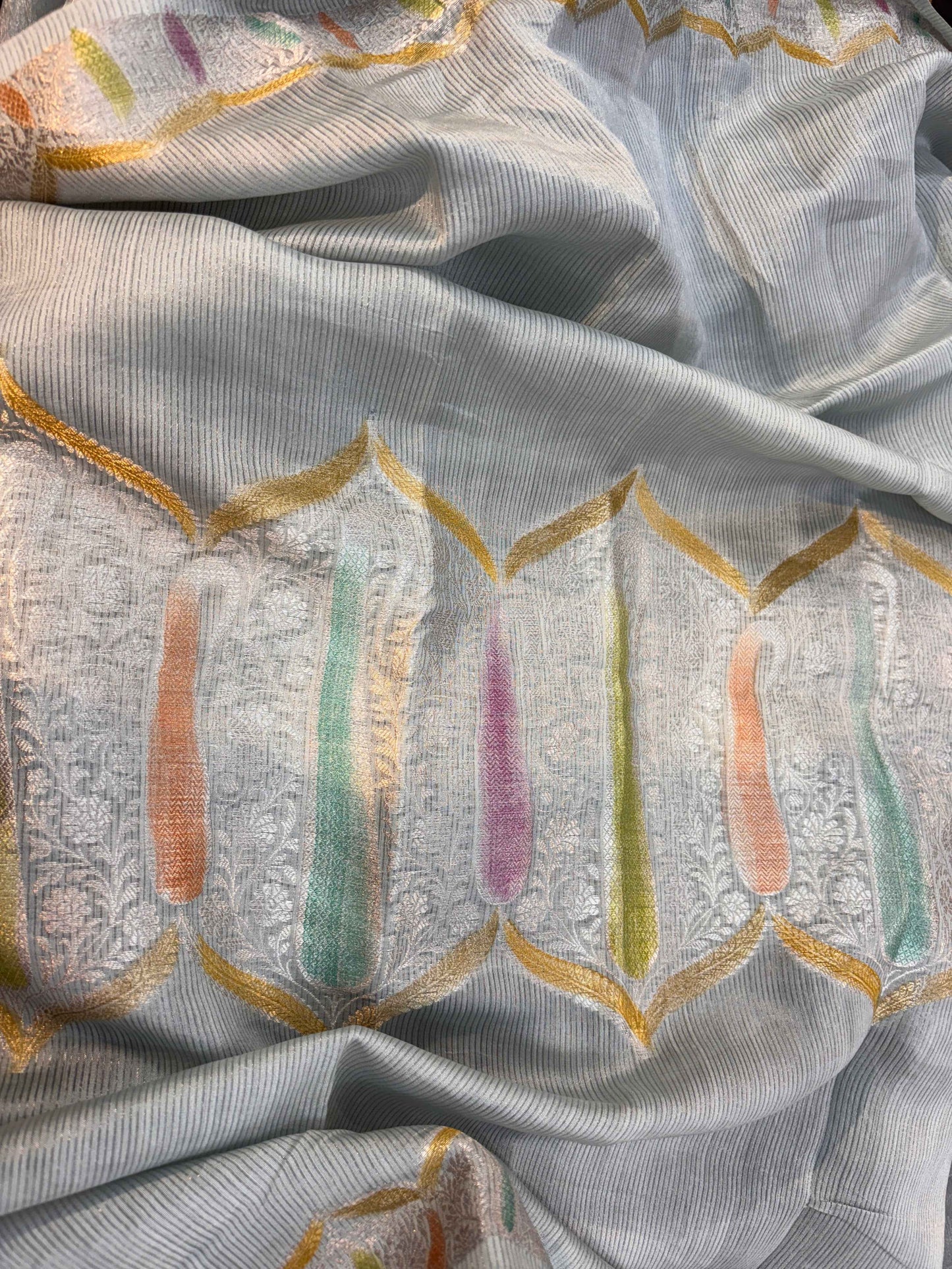 Gray saree fabric close-up with embroidered motifs and pastel vertical accents