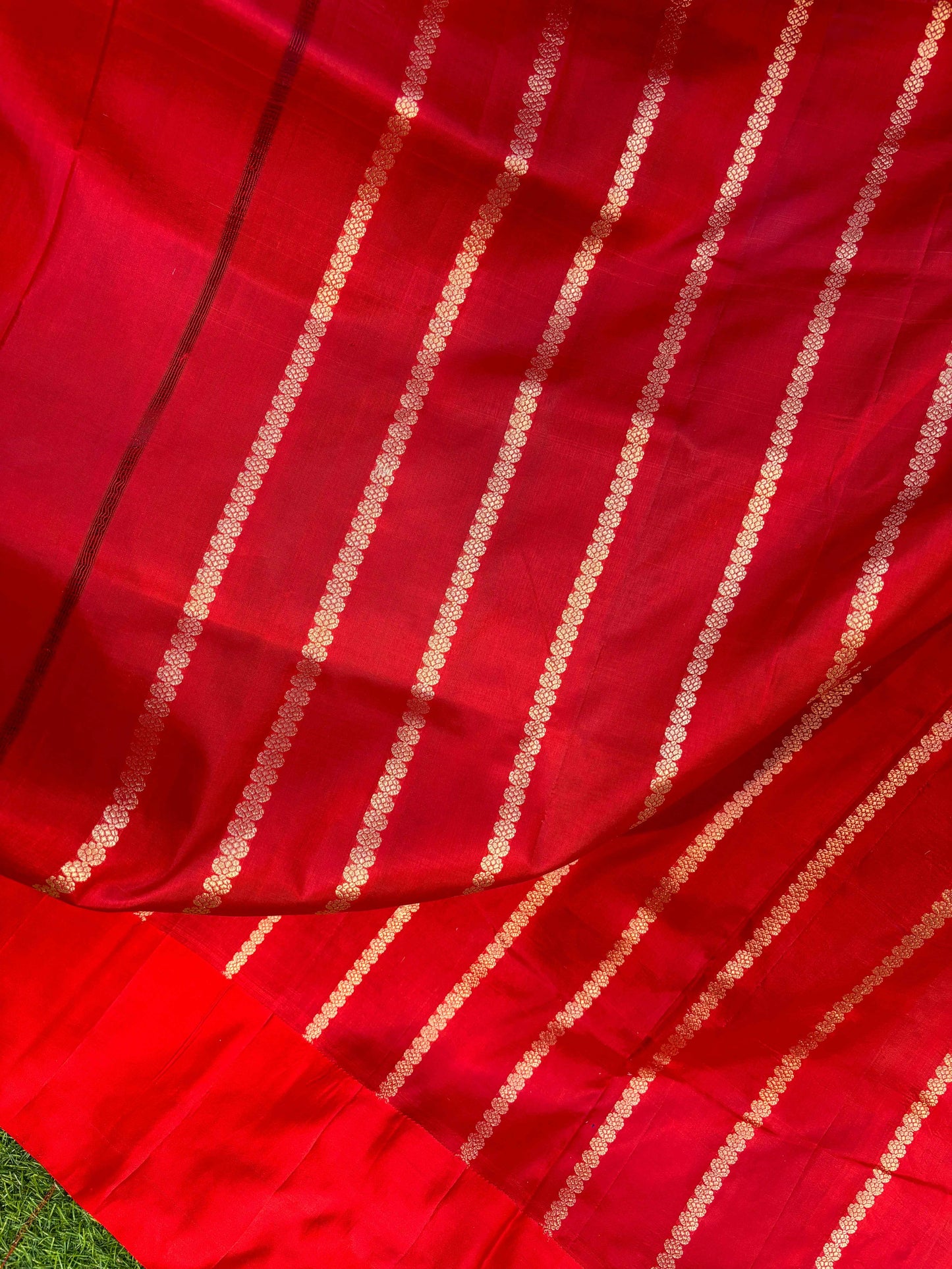 Red silk saree close-up with gold diagonal stripe and dotted zari border