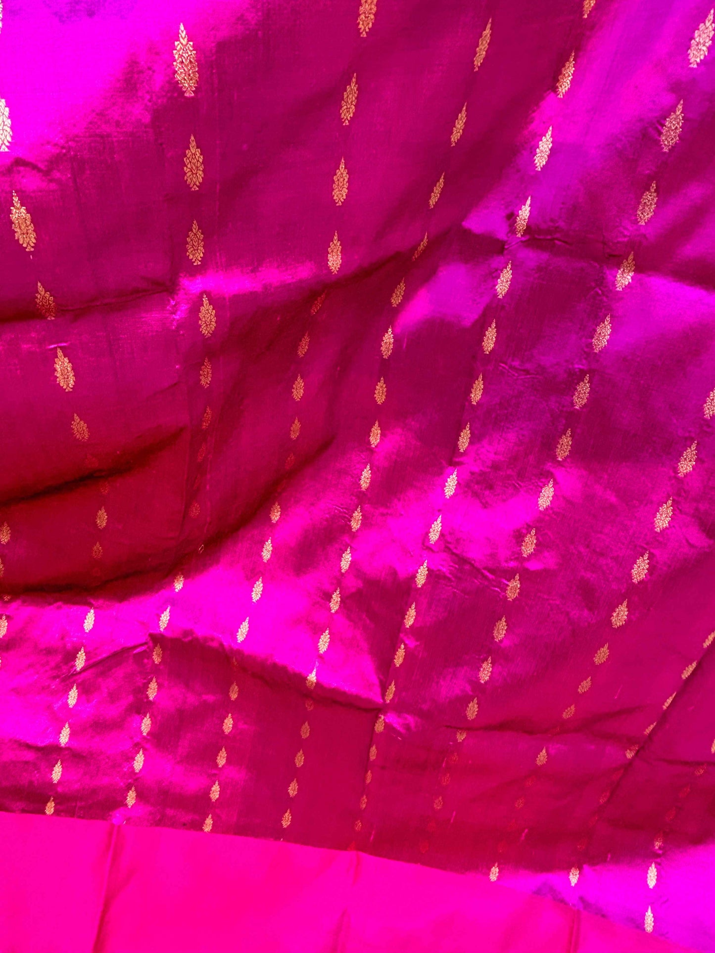Rani pink silk fabric with small gold motifs and woven texture, close-up