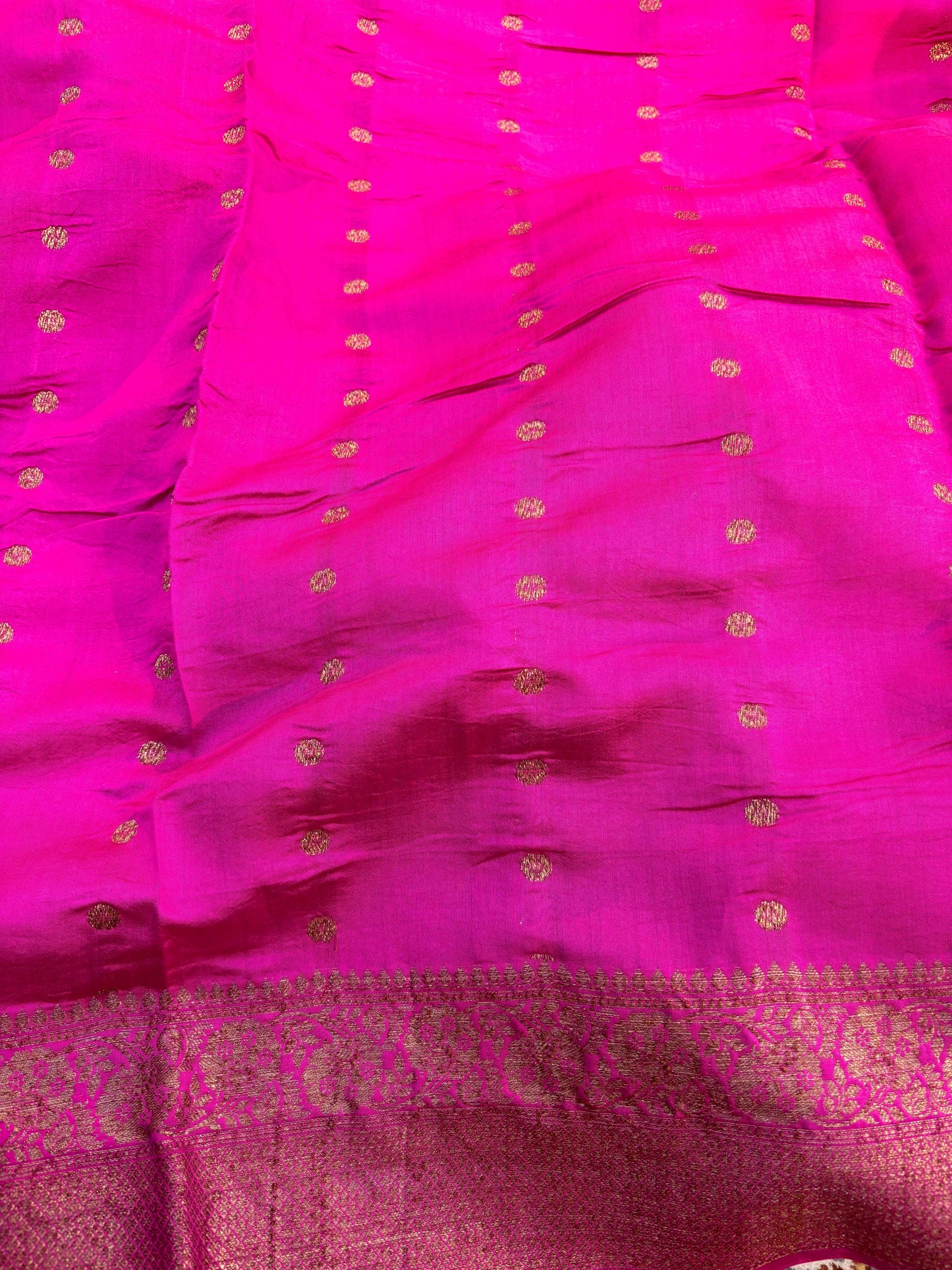 Rani pink silk saree with gold dot motifs and woven zari border hem.