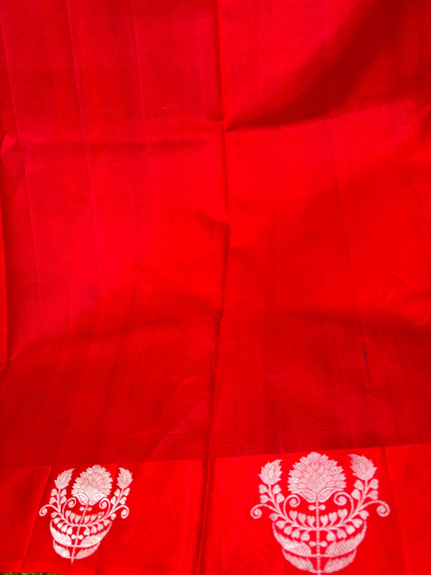 Red saree with stitched panels and white floral motif designs, folded close-up