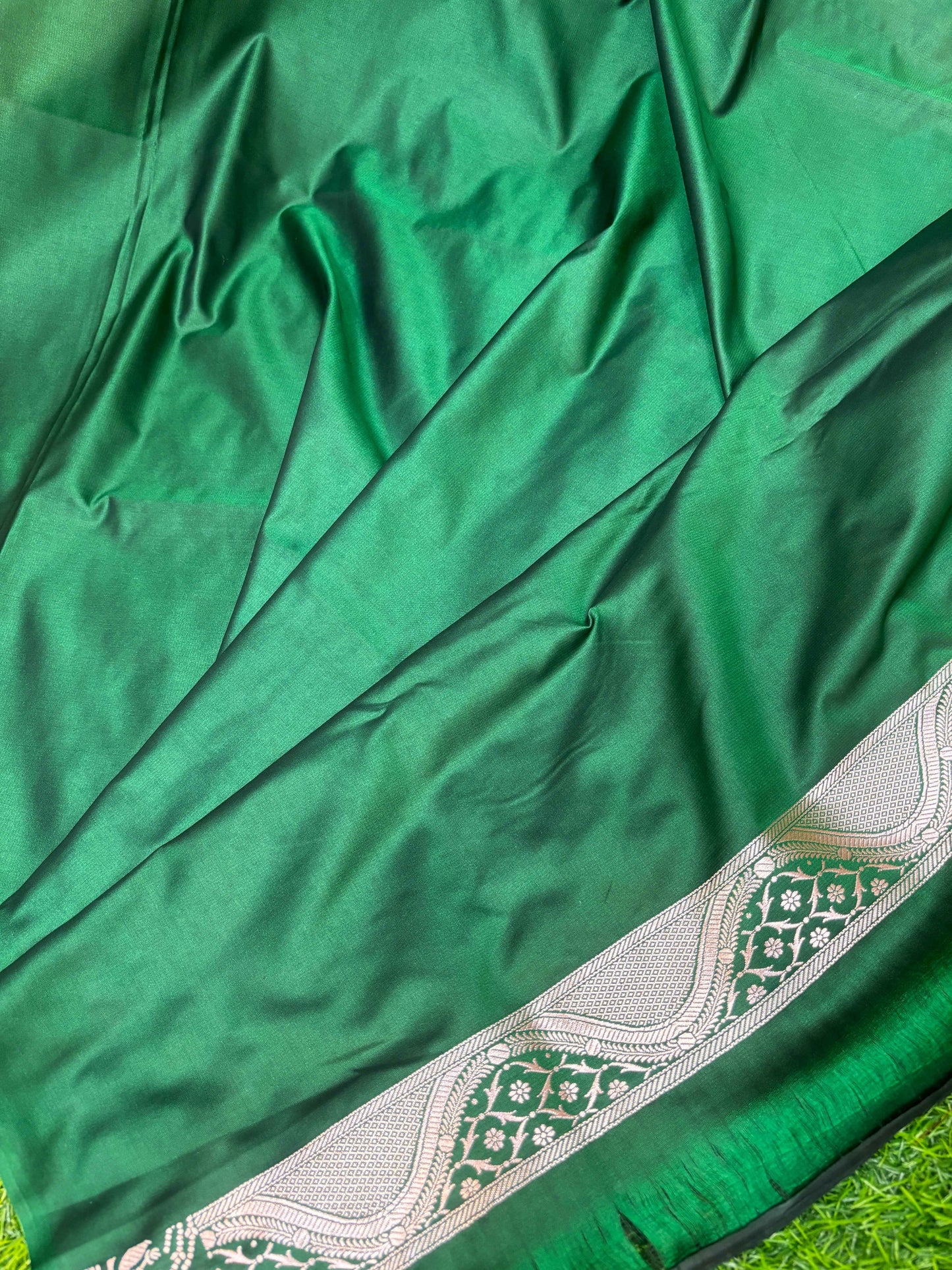 Green saree fabric with white floral border and textured sheen
