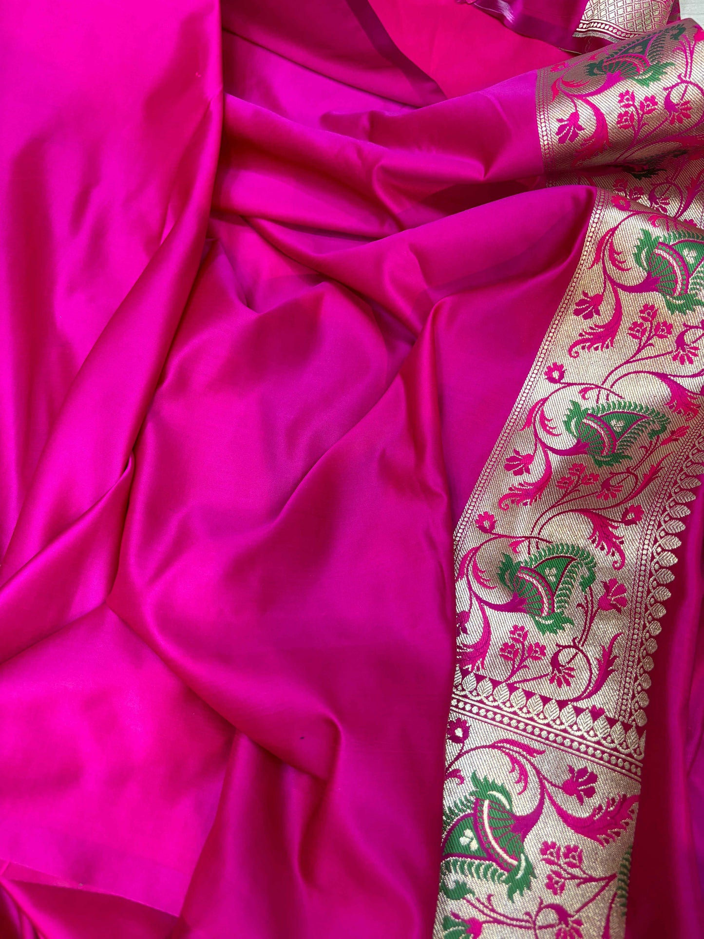 Magenta silk saree with green floral paisley border and woven zari trim, draped fabric