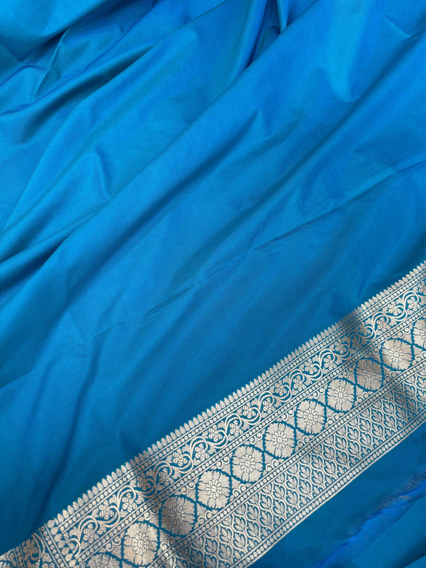Sky blue silk saree fabric close-up with woven zari line border