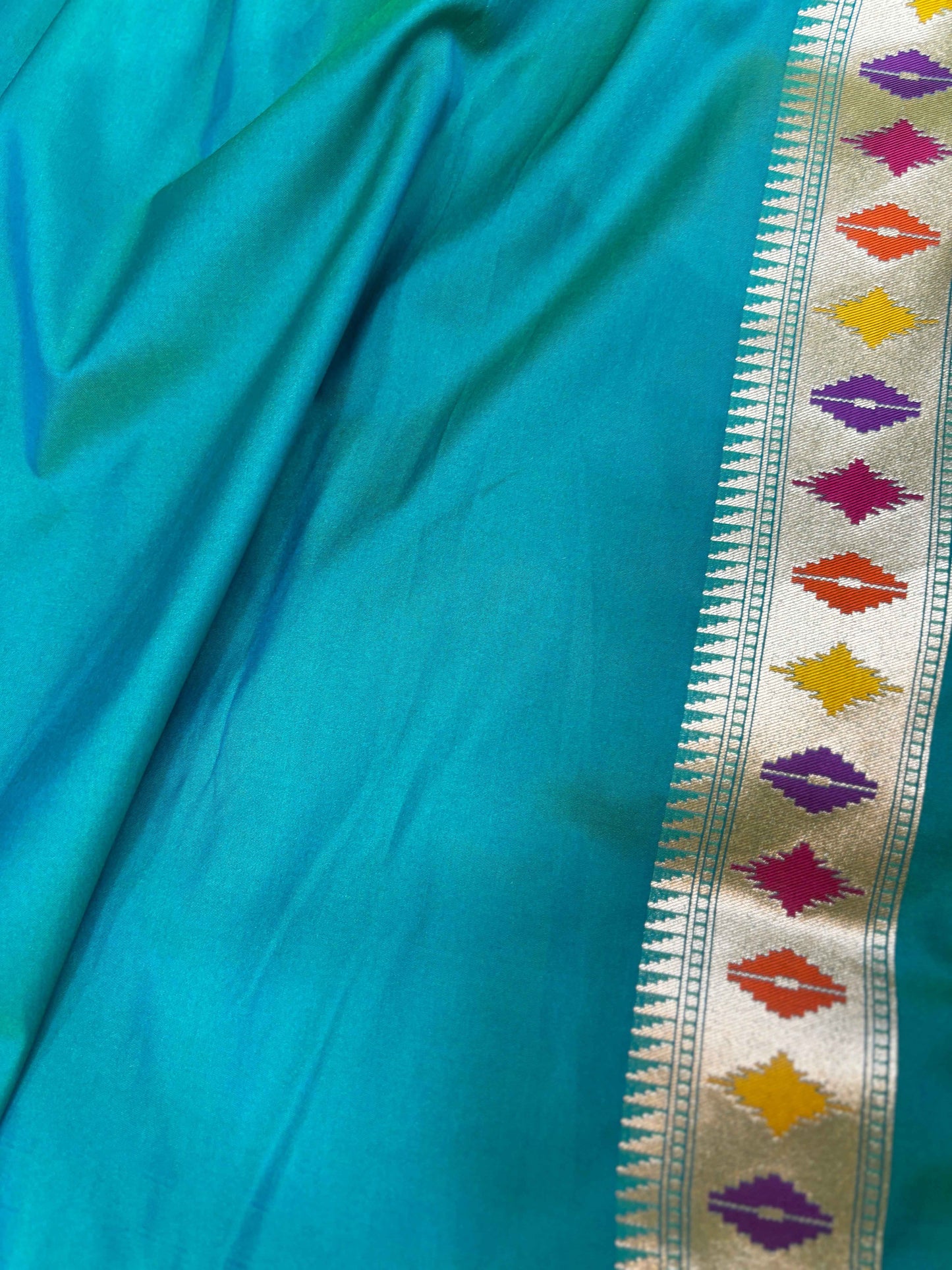 Teal fabric with multicolor geometric border detail and gold trim