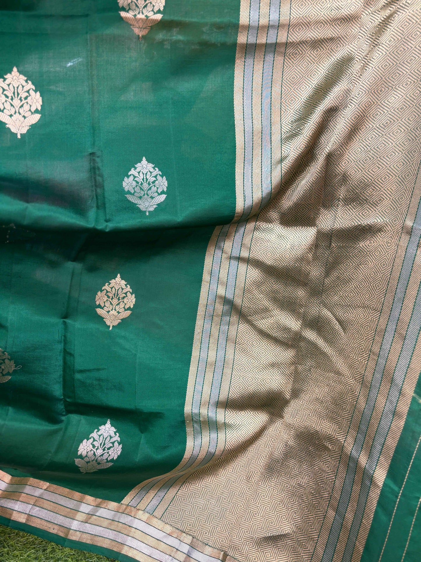 Green and beige saree close-up with gold floral motifs and striped trim