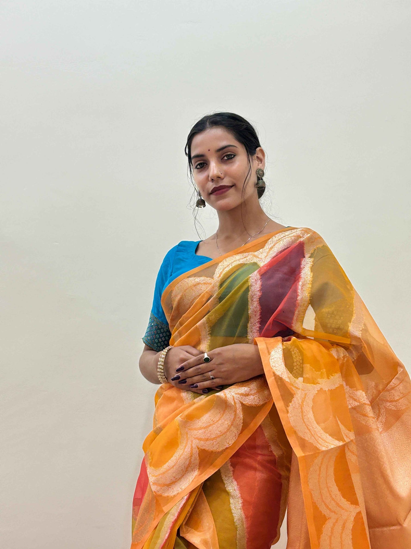 Orange silk saree with green and gold circular motifs and red accents